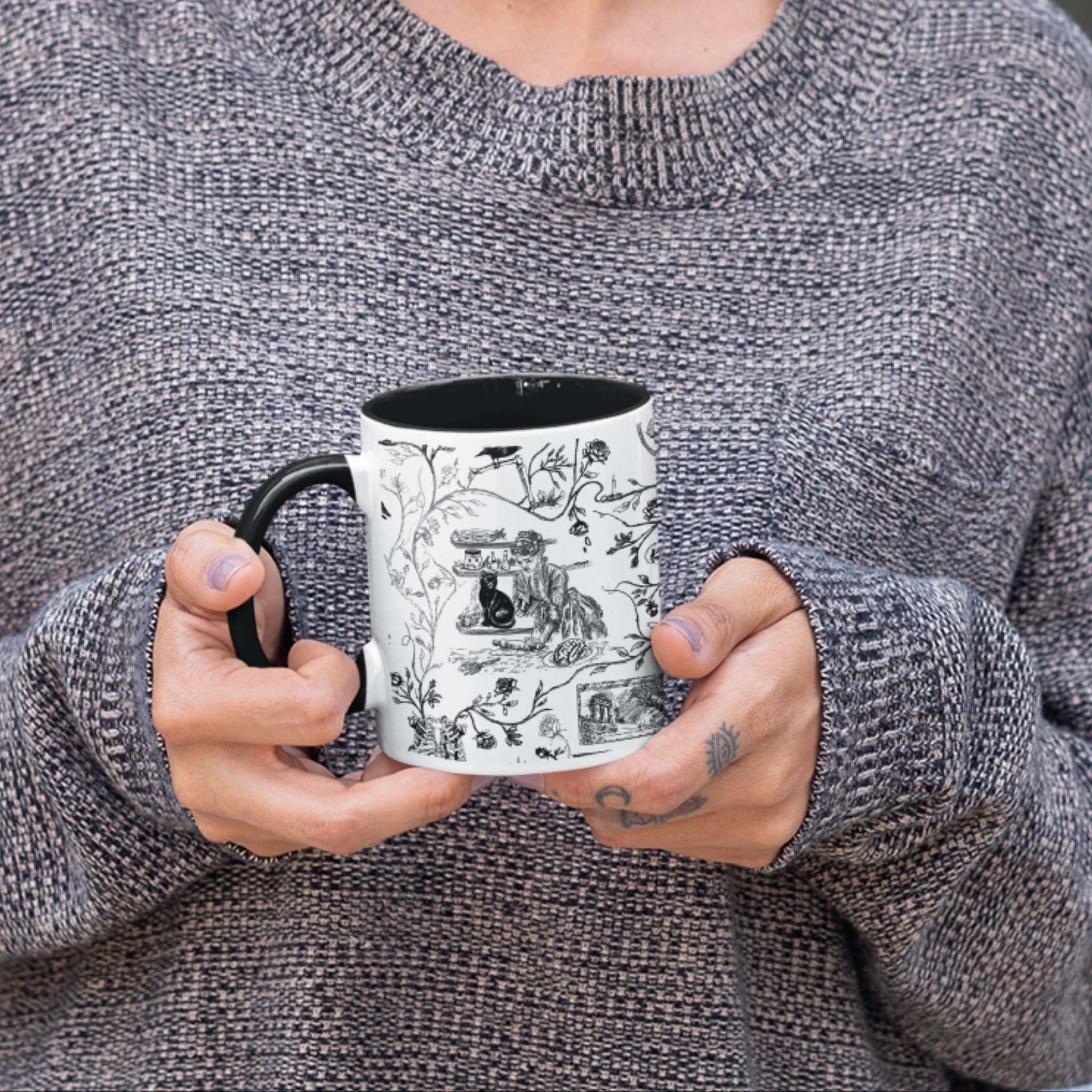 Person holding a black and white gothic toile zombie pattern mug with black handle