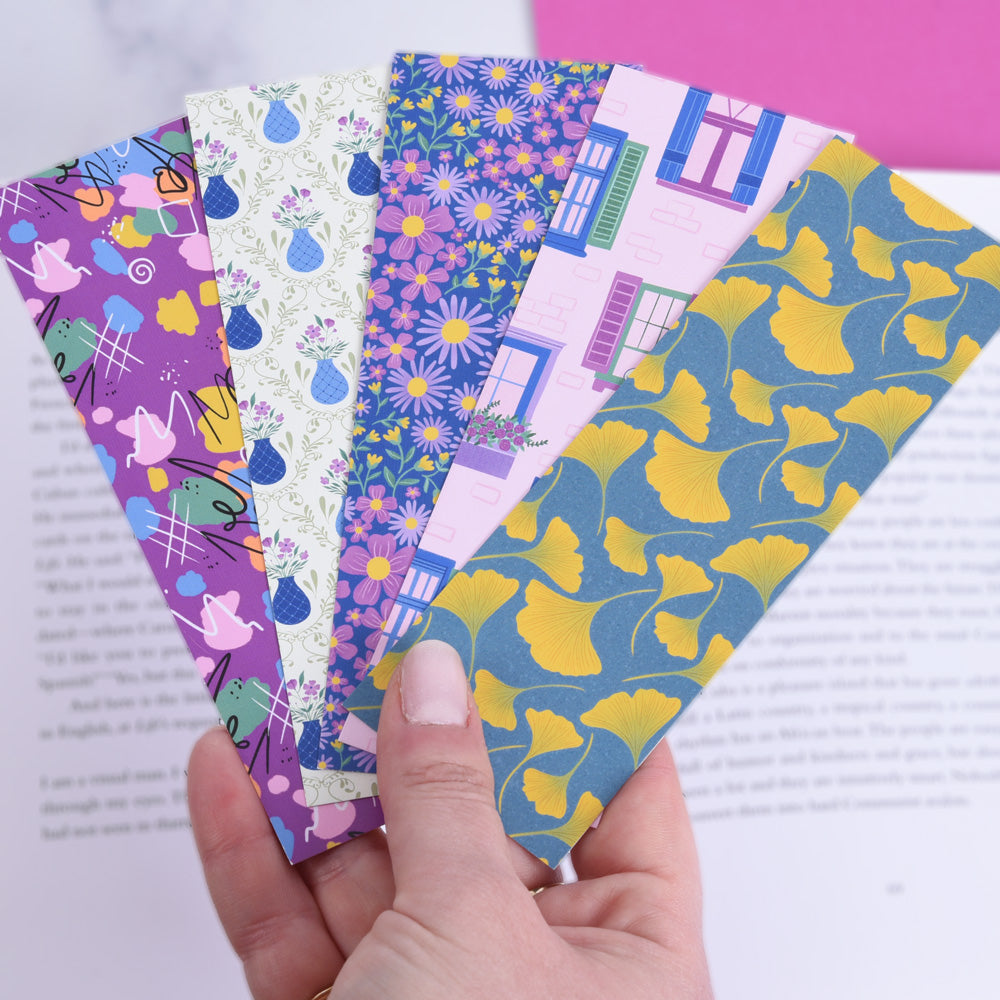 hand holding fanned out bookmarks in front of an open book