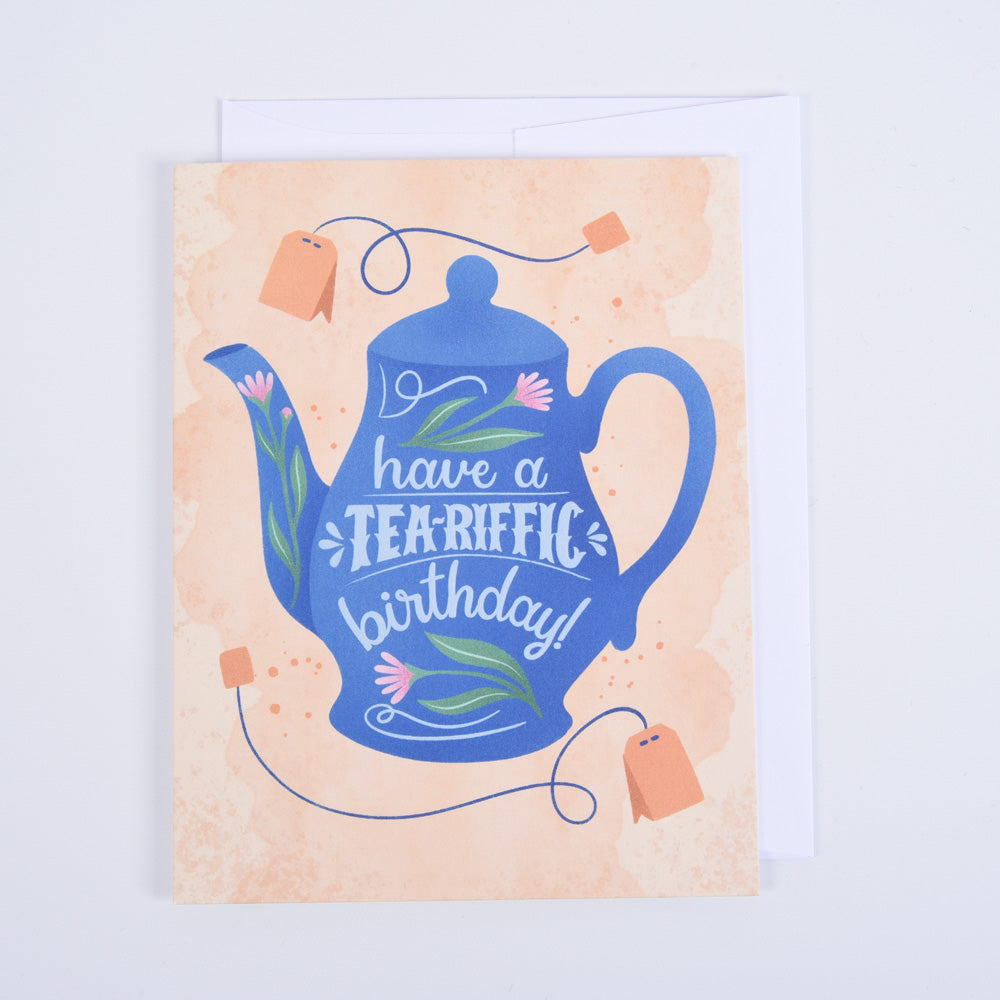 A folded greeting card with a blue teapot illustration and &