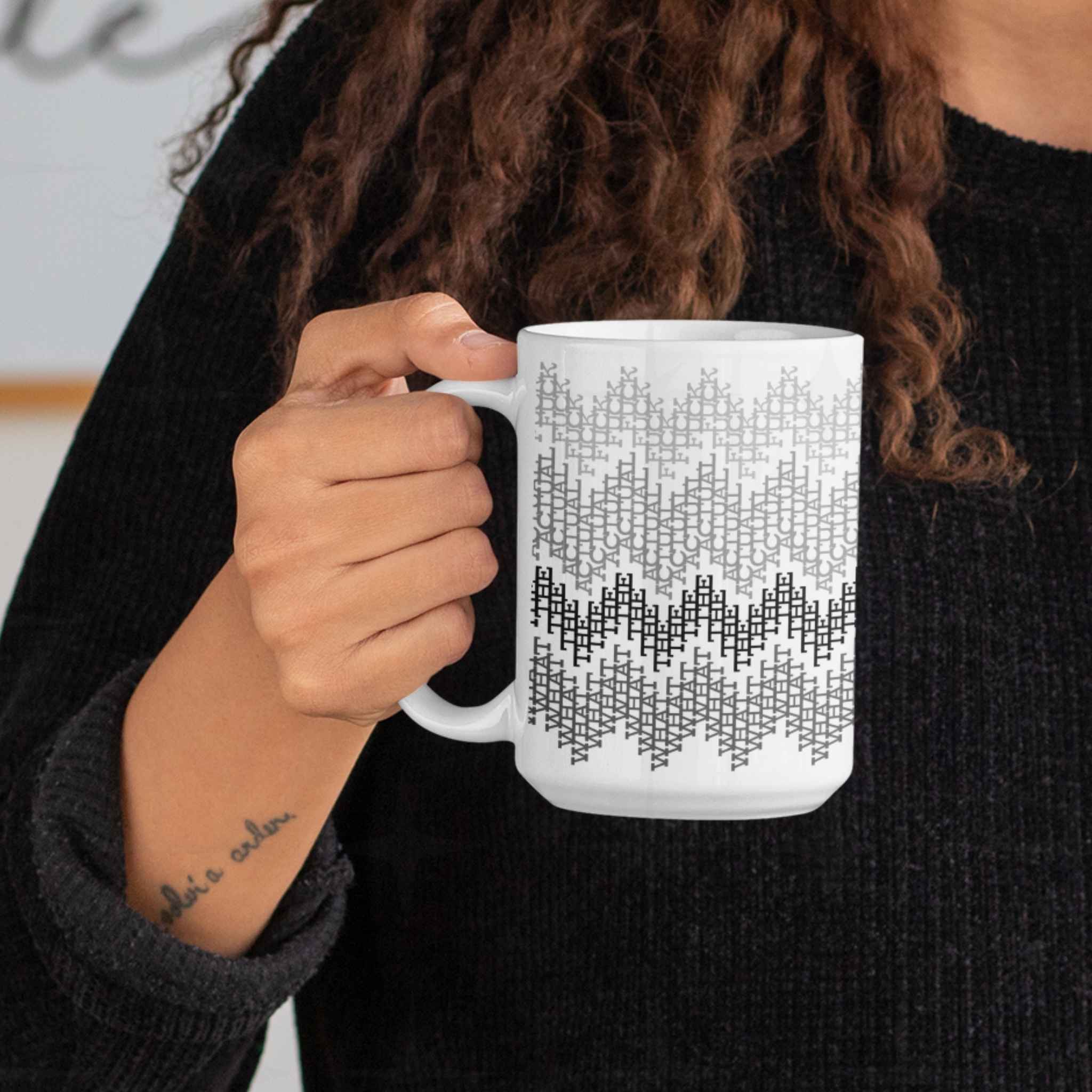 Woman holding gray monochrome hidden profanity mug close to her chest, cozy indoor lifestyle setting