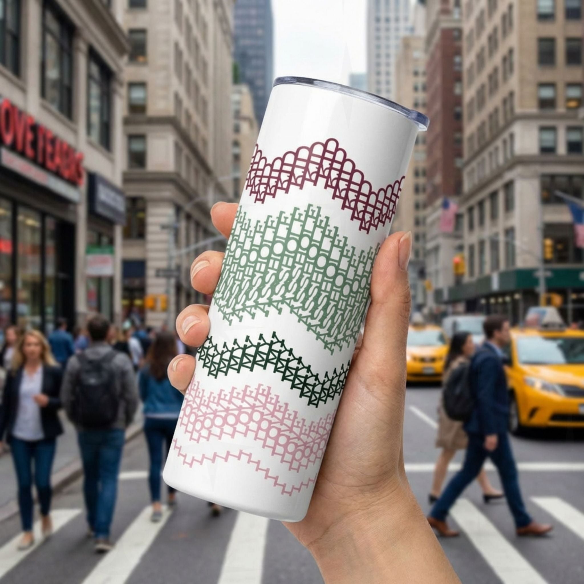 Preppy Stripes hidden message tumbler held up on a busy city street — burgundy, sage green, dark forest green, and blush pink chevron band pattern wraps the white 20oz skinny tumbler
