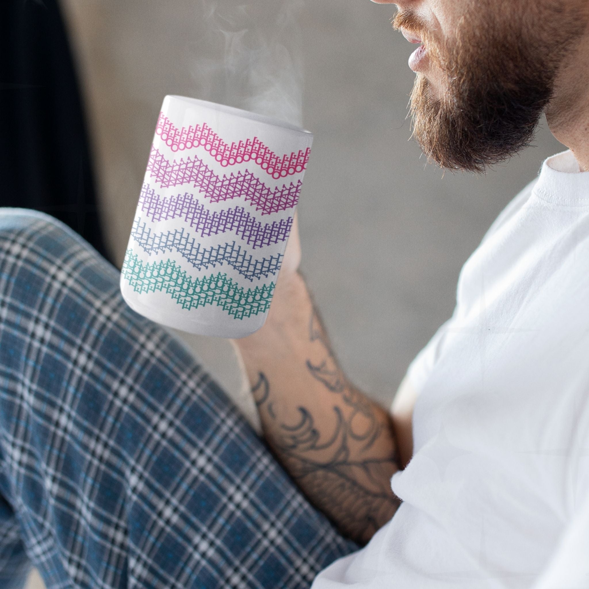 Bearded man with arm tattoos drinking from bright stripes hidden profanity chevron mug in hot pink purple and teal, steam rising
