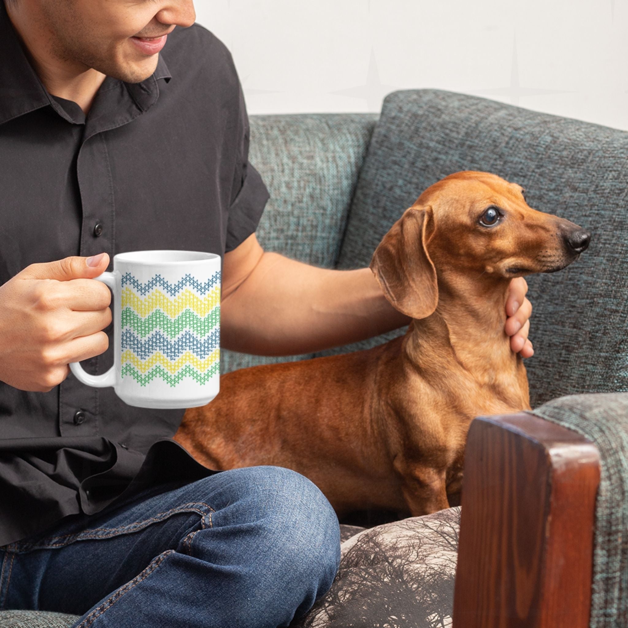 Person relaxing on couch with dachshund holding hidden profanity coffee mug in bright teal yellow green cross stitch pattern