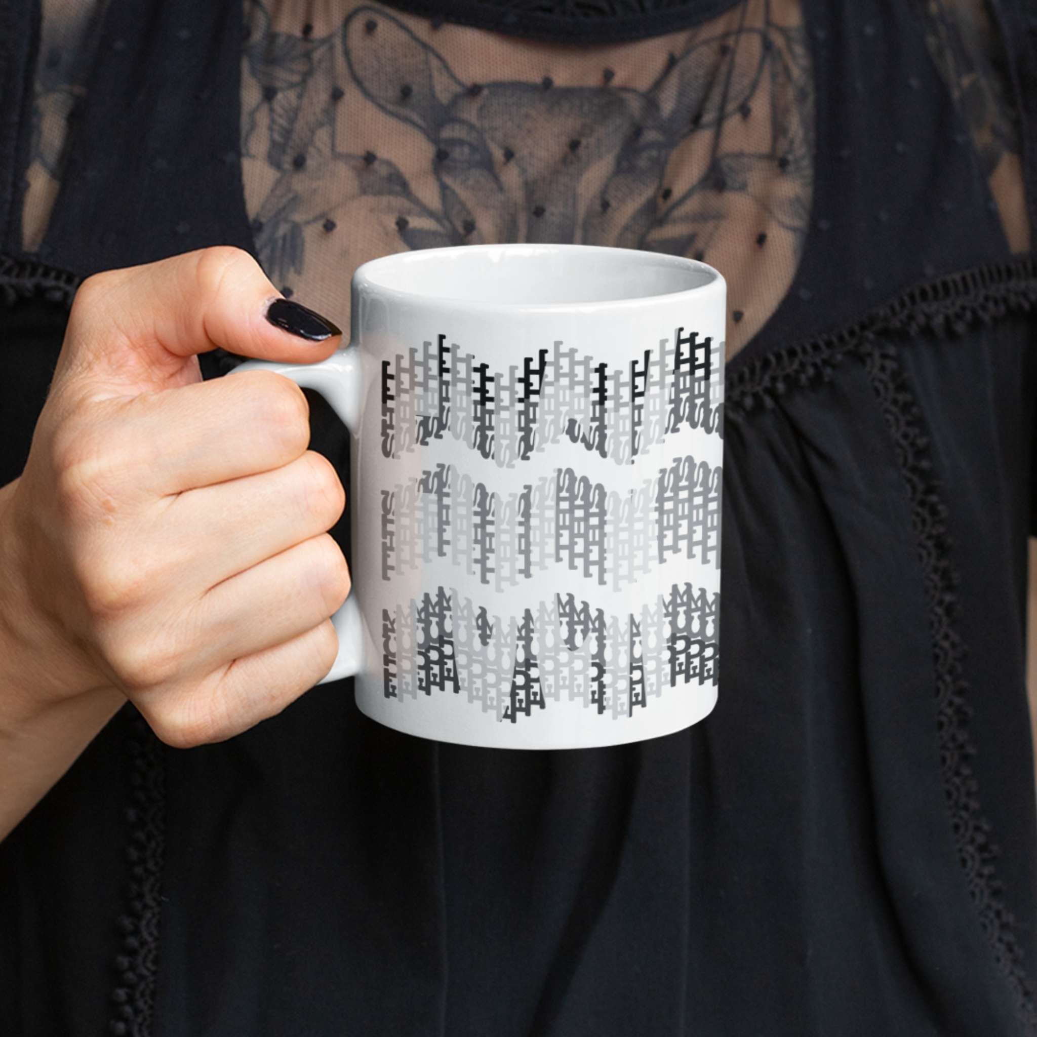 Woman in black lace top holding 11oz hidden profanity coffee mug with grayscale typographic design