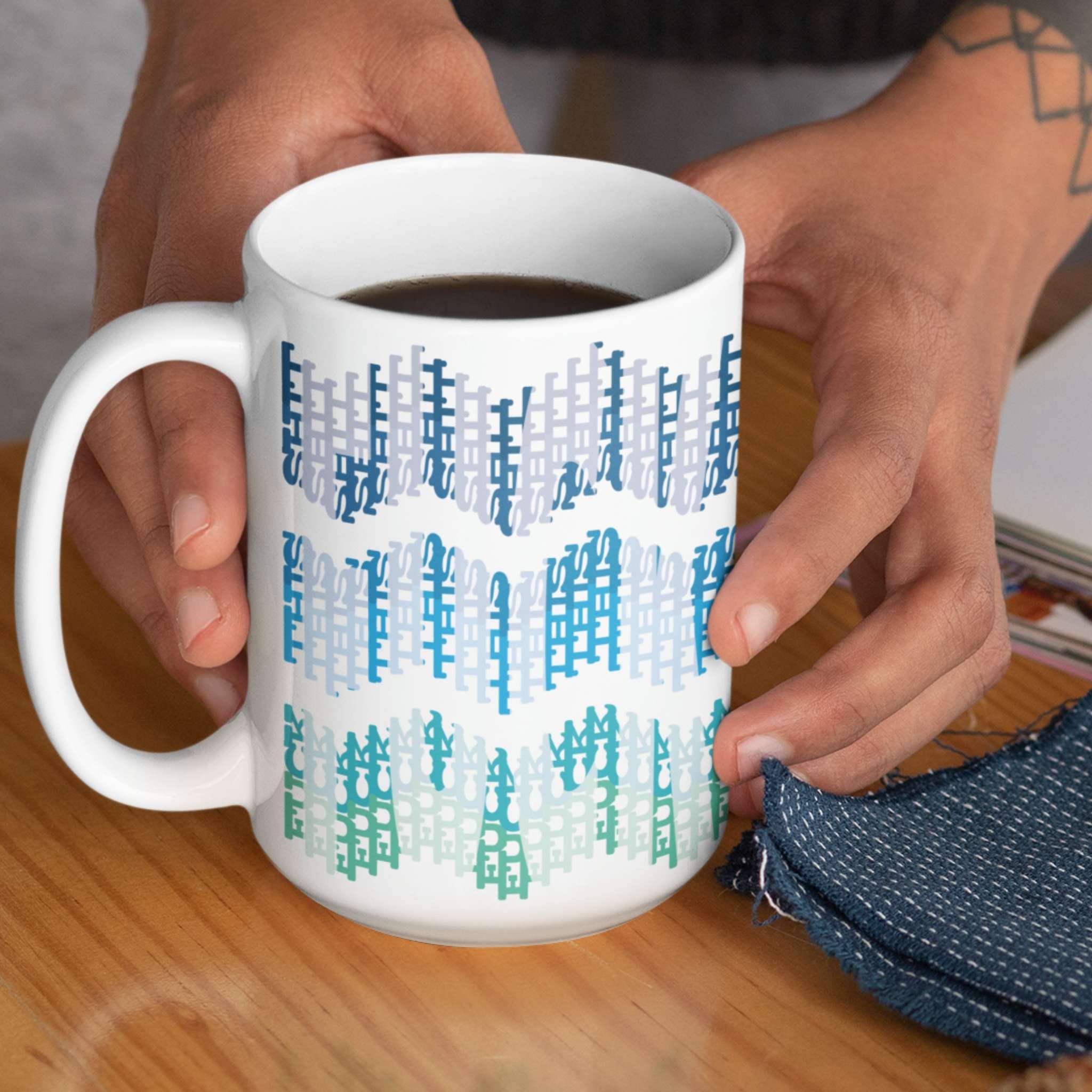 Person holding 15oz hidden profanity coffee mug with ocean ombre typographic chevron design filled with black coffee