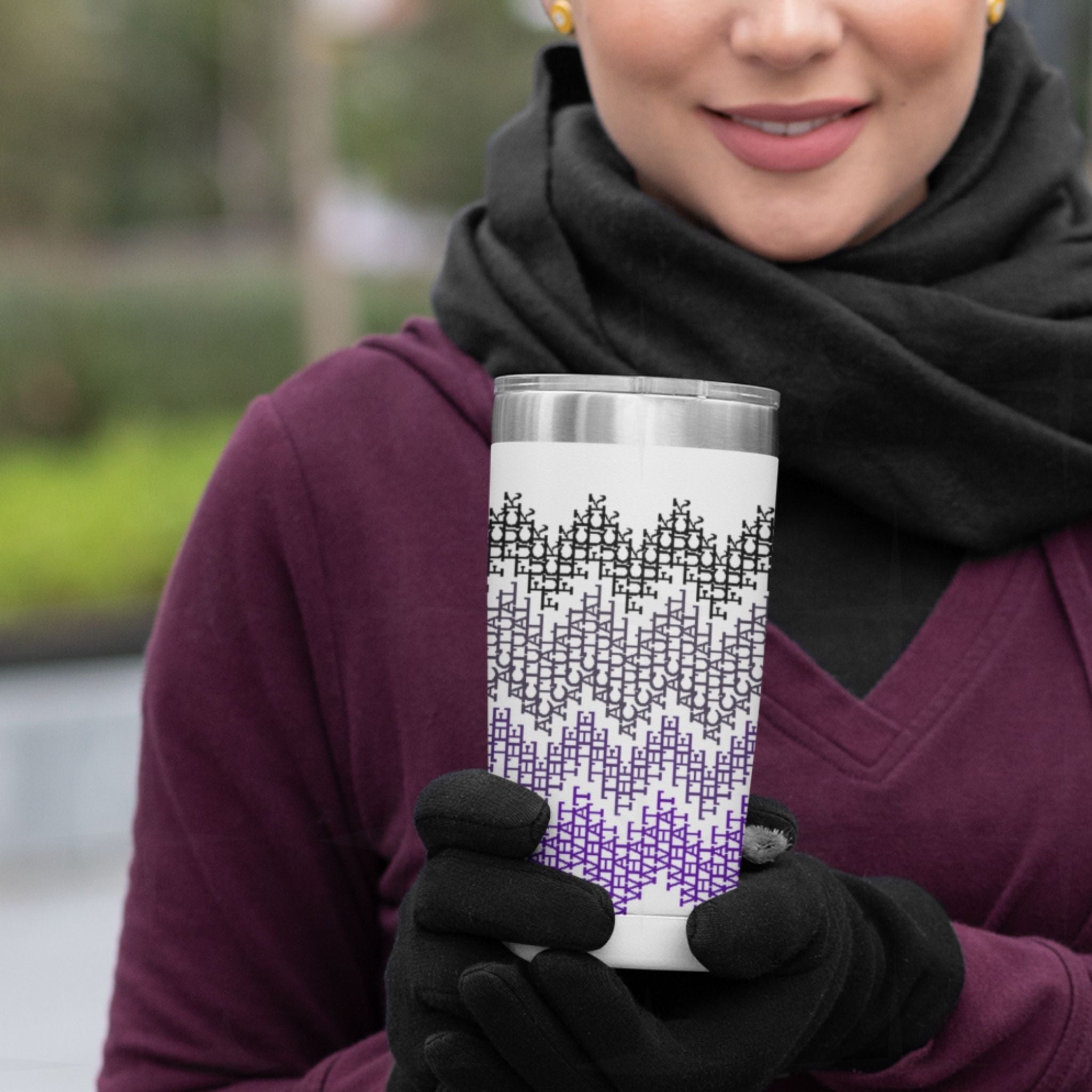 Woman in burgundy coat and black gloves holding purple ombre hidden profanity tumbler outdoors, fair isle swear word pattern visible
