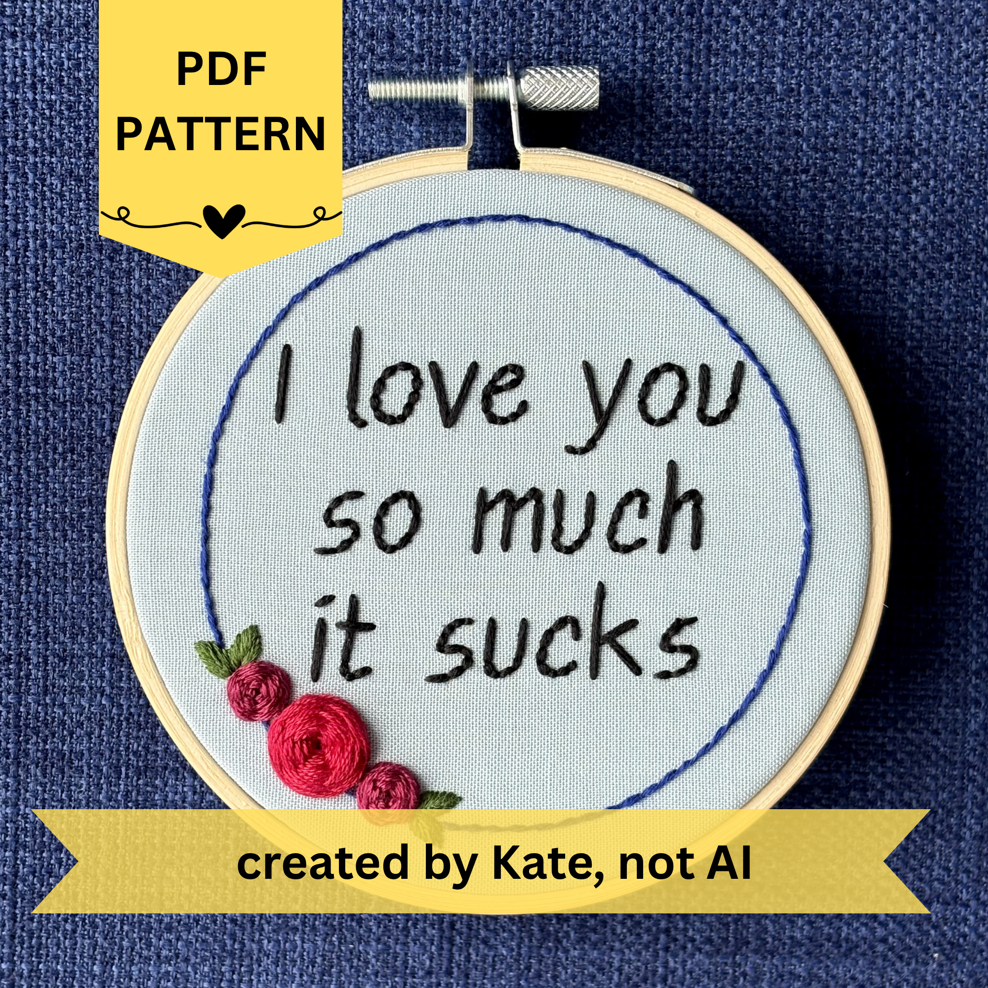 PDF pattern created by Kate, not AI. "I love you so much it sucks." Quote hand embroidered in handwriting font in black embroidery thread. Around the text is a floral wreath of a blue ring, red roses and green leaves. Fabric is light blue, and completed embroidery is displayed in a light wood embroidery hoop.