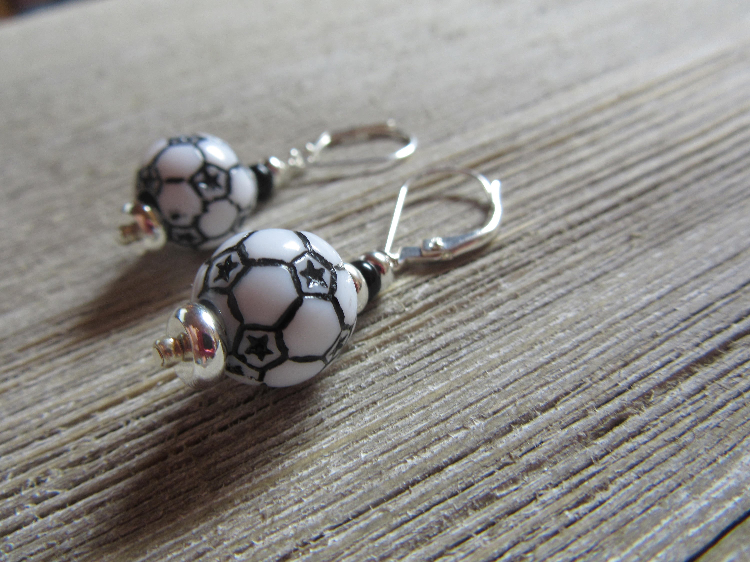 Flat lay of Soccer Ball Earrings showcasing their dangle design - Sports Theme Jewelry - Novelty Women Accessories by Enlivenadorn by Gwynstone.