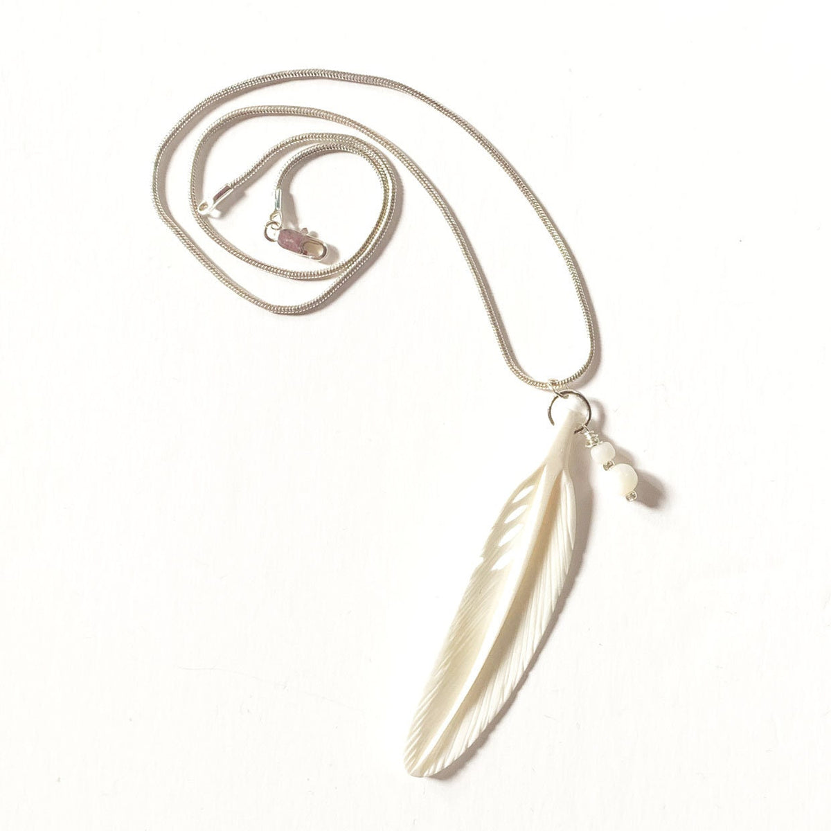 White Feather Necklace featuring a carved bone and mother of pearl pendant, symbolizing purity and strength, ideal for any outfit.