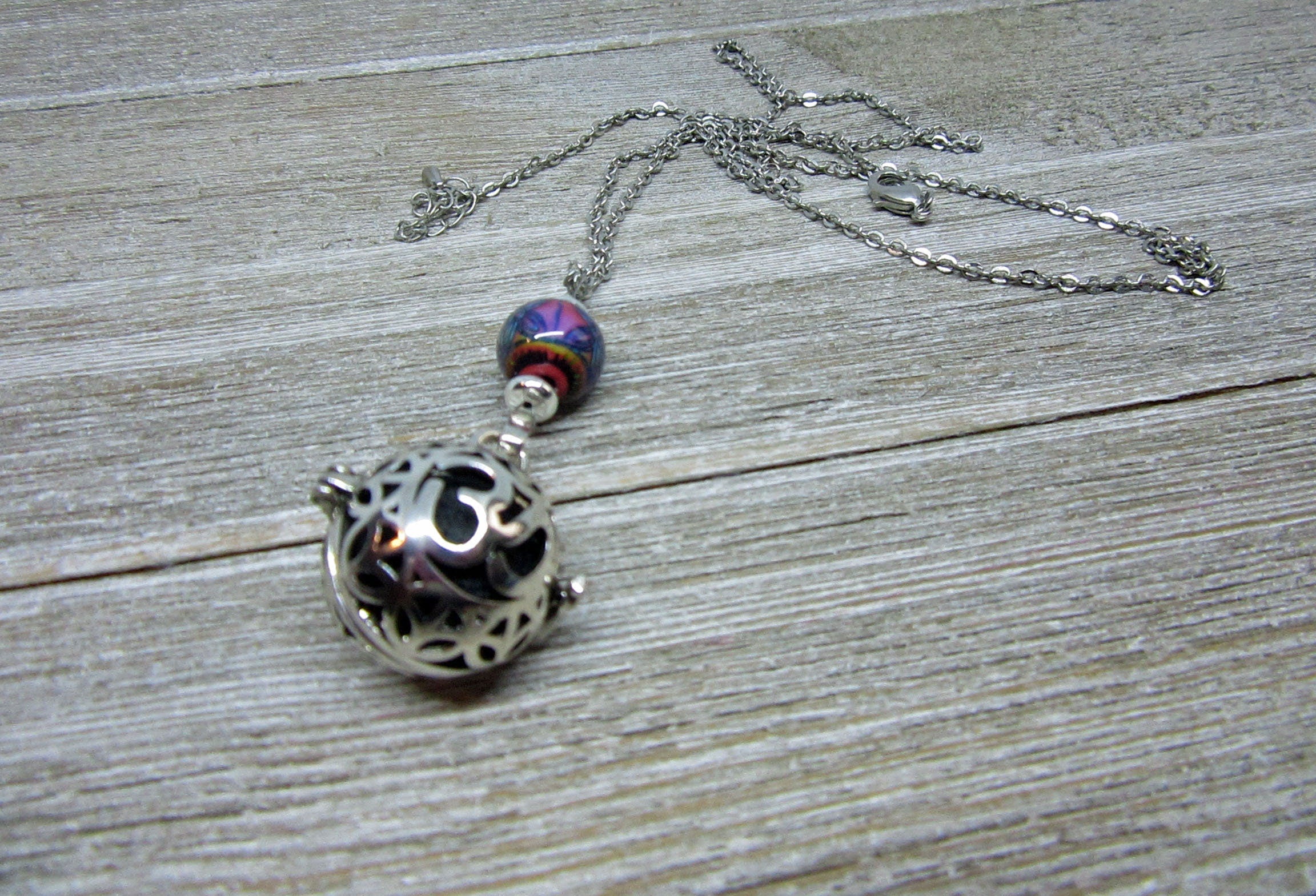Display of the Namaste Symbol Color Changing Essential Oil Diffusing Zen Chamber Necklace in bright natural lighting, emphasizing its unique color changing property.