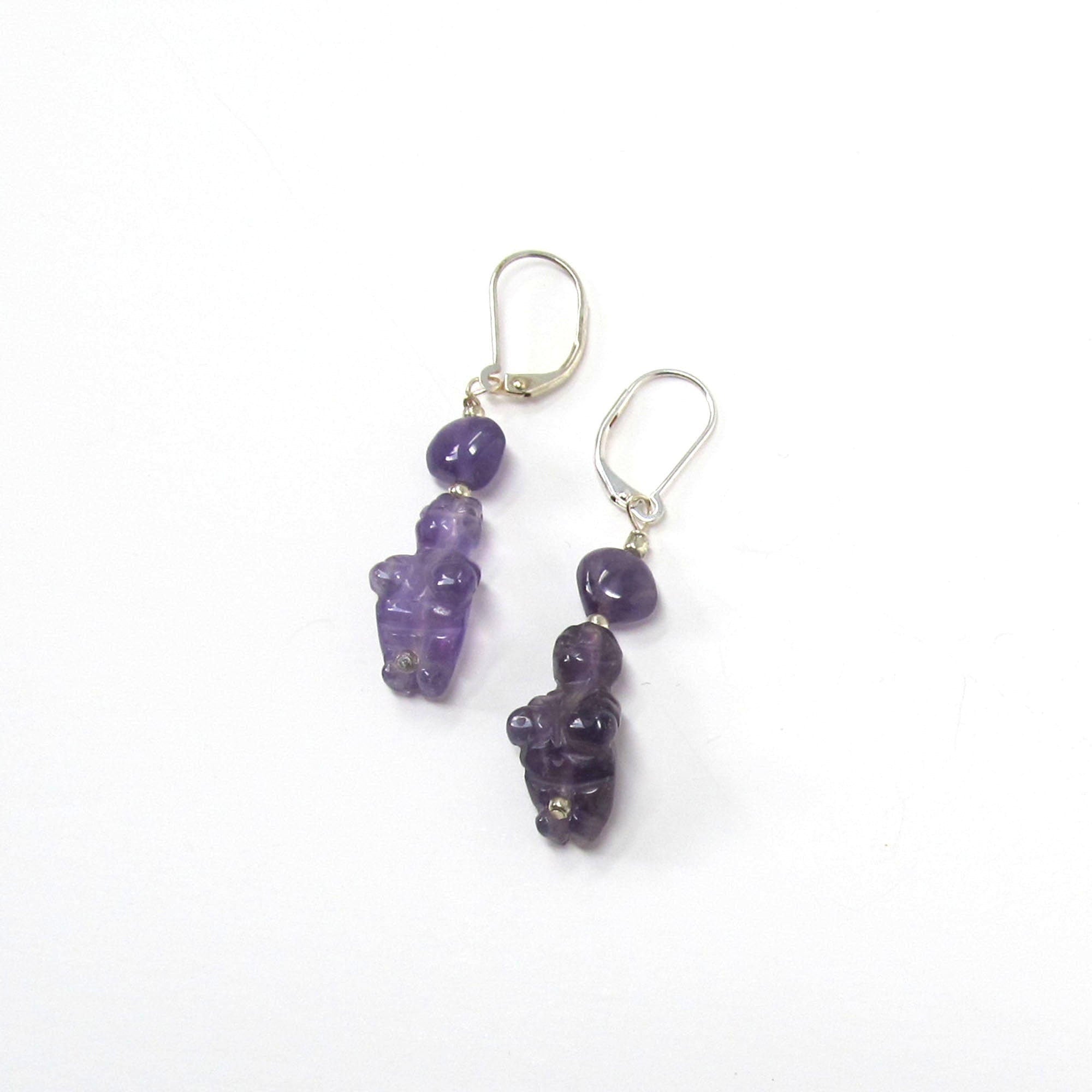 The Handcrafted Amethyst Goddess Earrings: Willendorf Venus Jewelry feature silver hooks with dangling purple gemstone beads, each uniquely shaped, adding artisanal charm and elegance to any outfit.