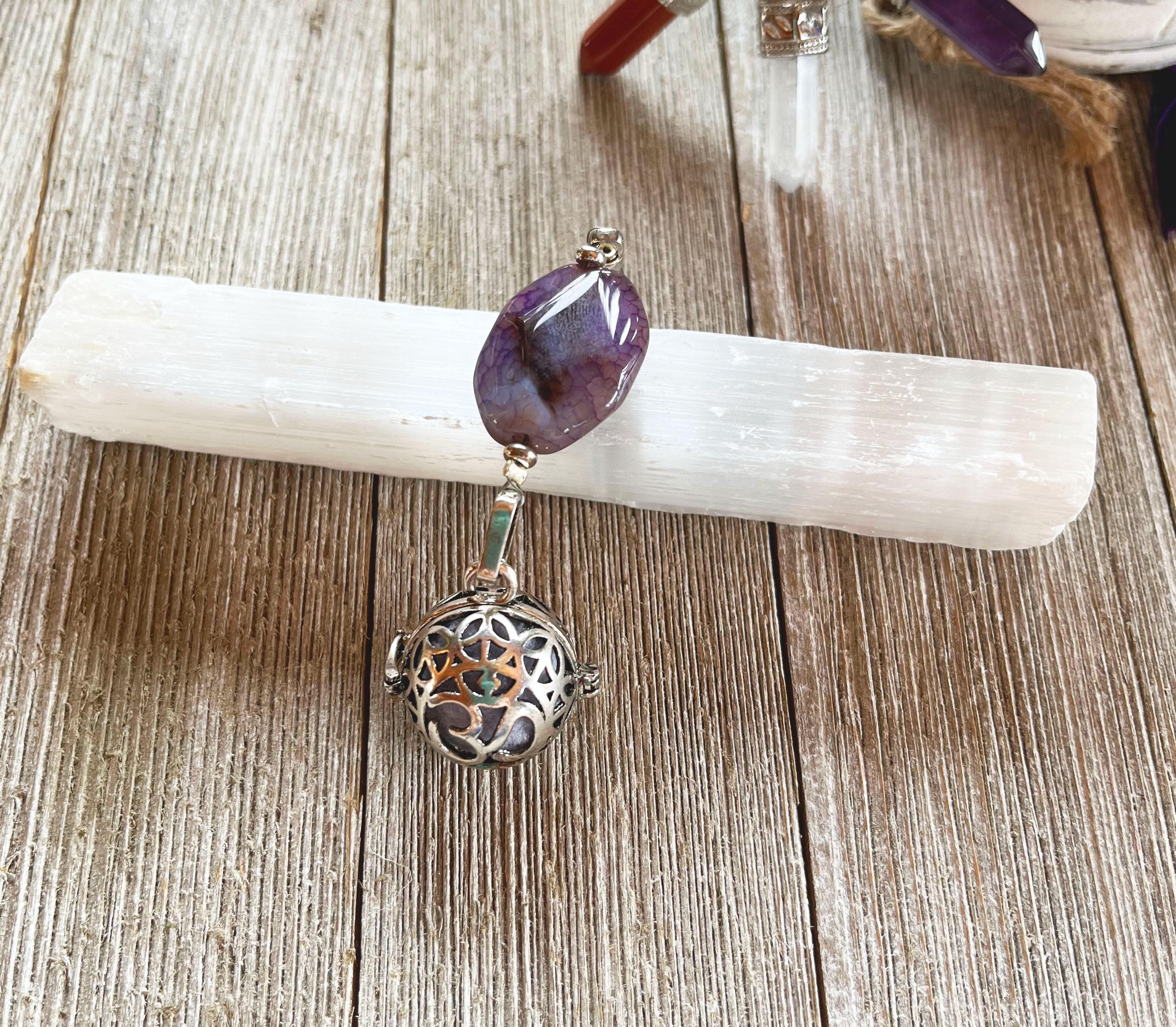The Handcrafted Zen Aromatherapy Chamber features a large purple agate stone and a round, detailed Namaste symbol, presented on a white crystal base atop a wooden surface.