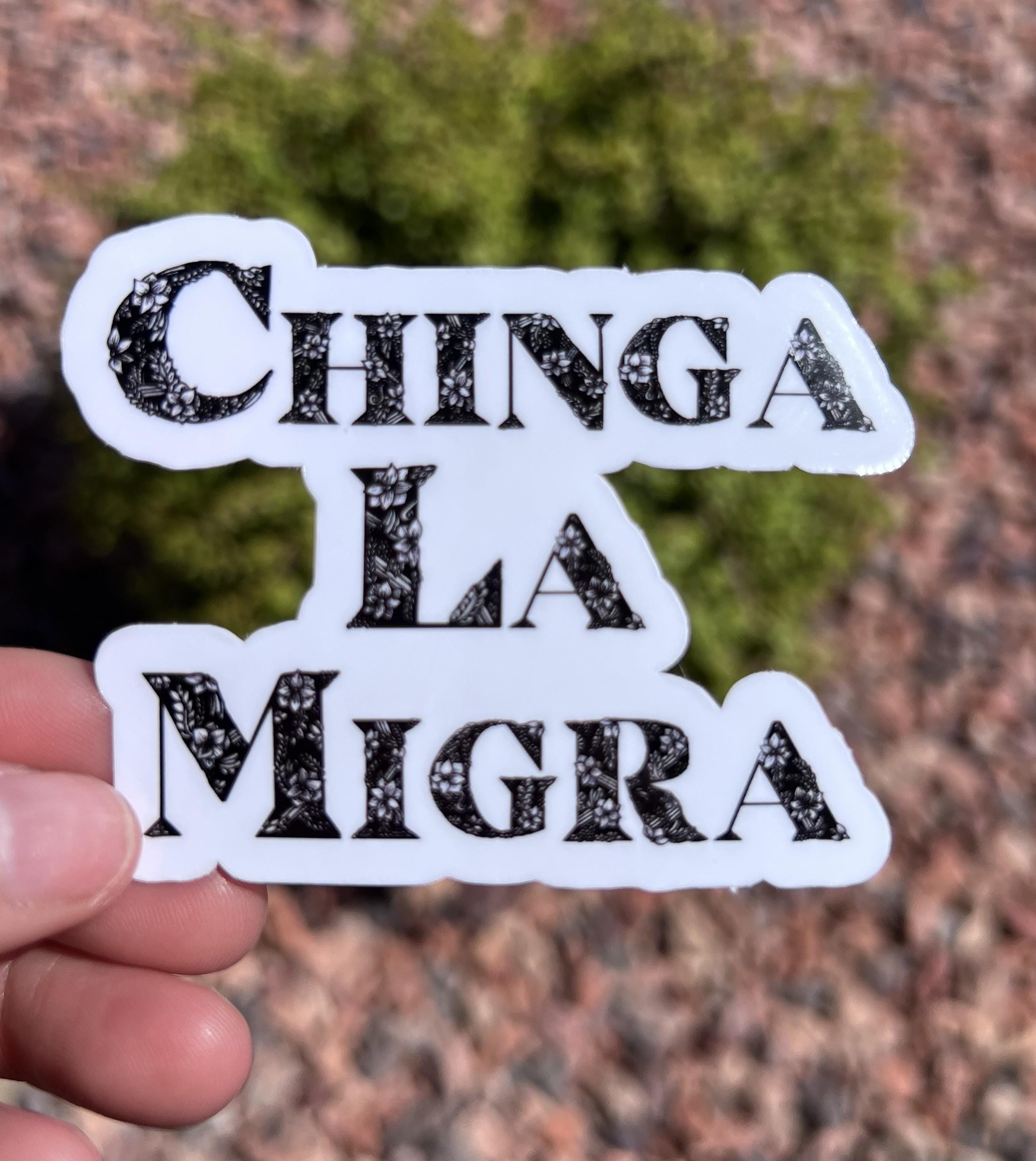 May include: A white sticker with the words "CHINGA LA MIGRA" in black, floral-patterned letters.