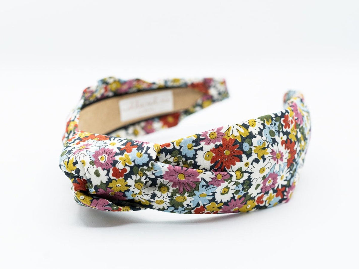 May include: A floral headband with a knotted design. The headband has a label that says "MADDIE AND ME".