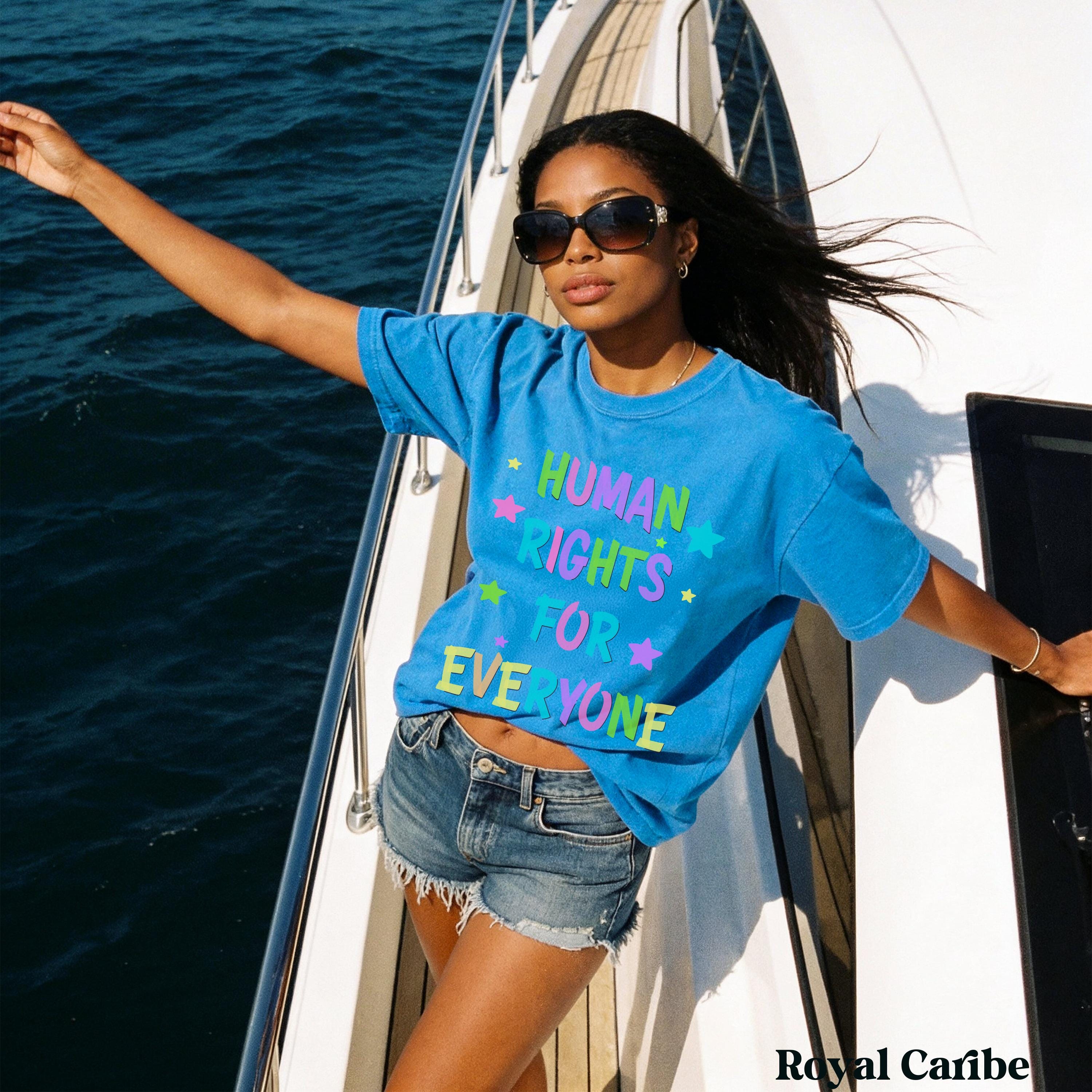 Blue t-shirt with colorful "Human Rights for Everyone" text, worn by a woman on a yacht.