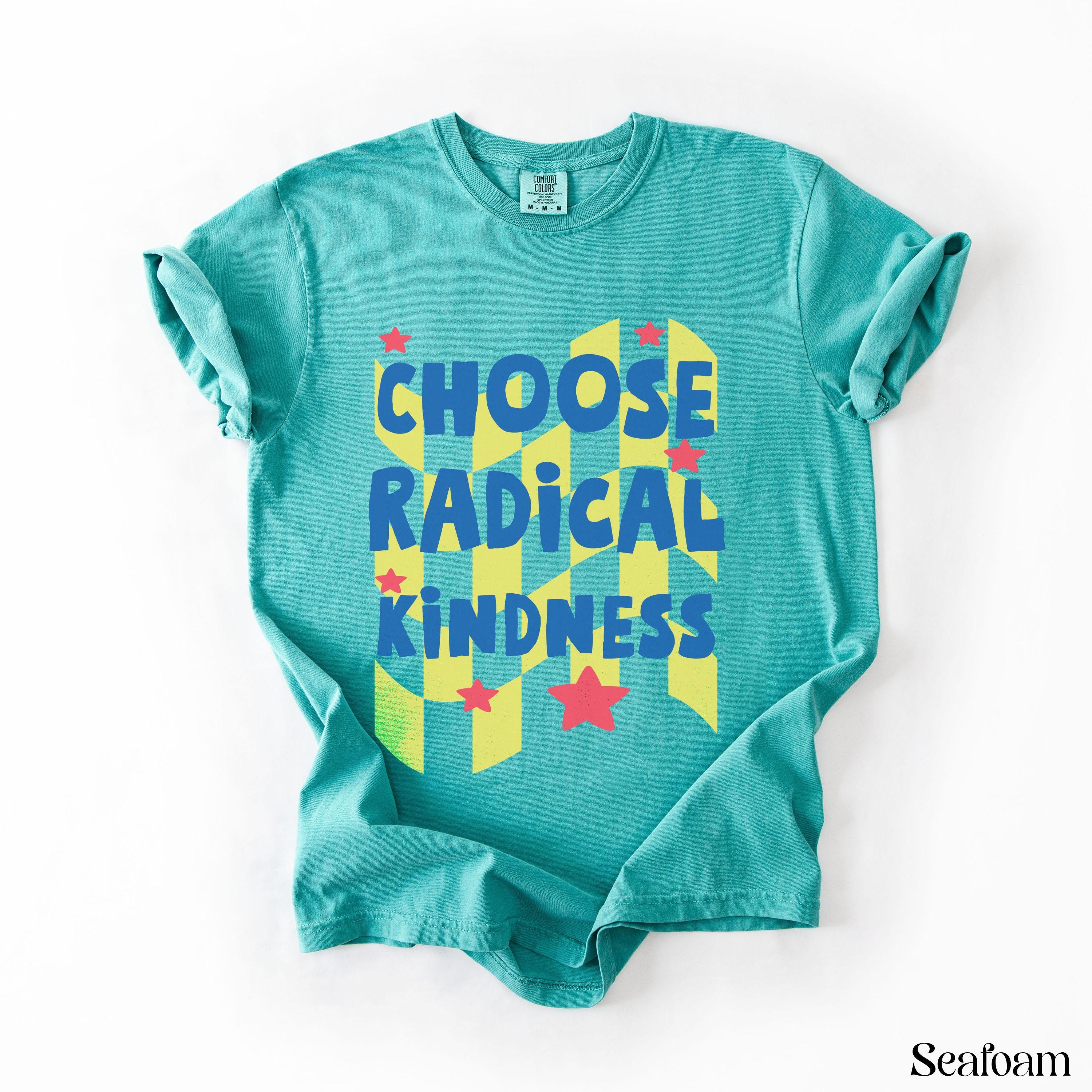 Teal t-shirt with yellow and blue geometric pattern and "CHOOSE RADICAL KINDNESS" text.