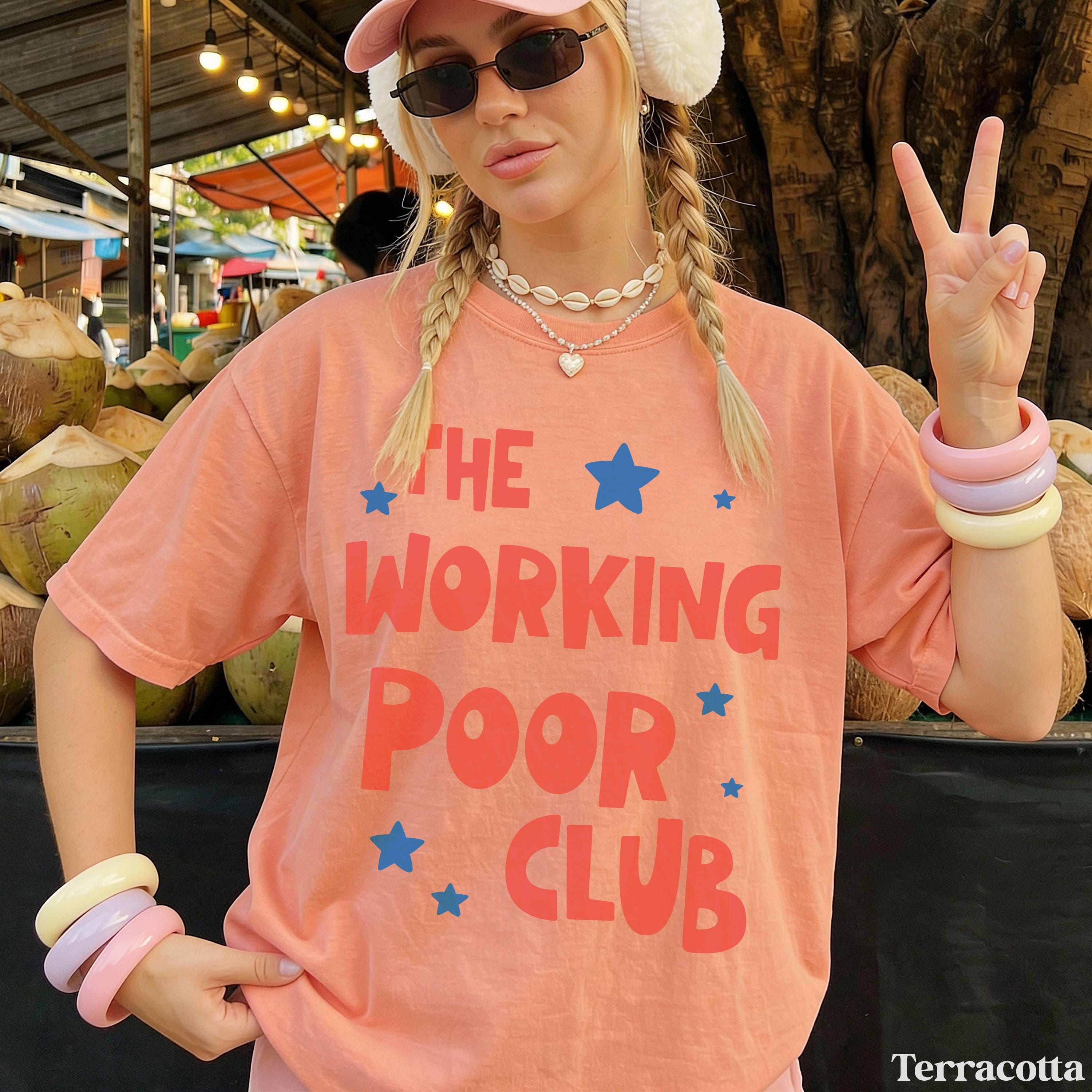 Woman wearing "The Working Poor Club" graphic tee, holding up peace sign.