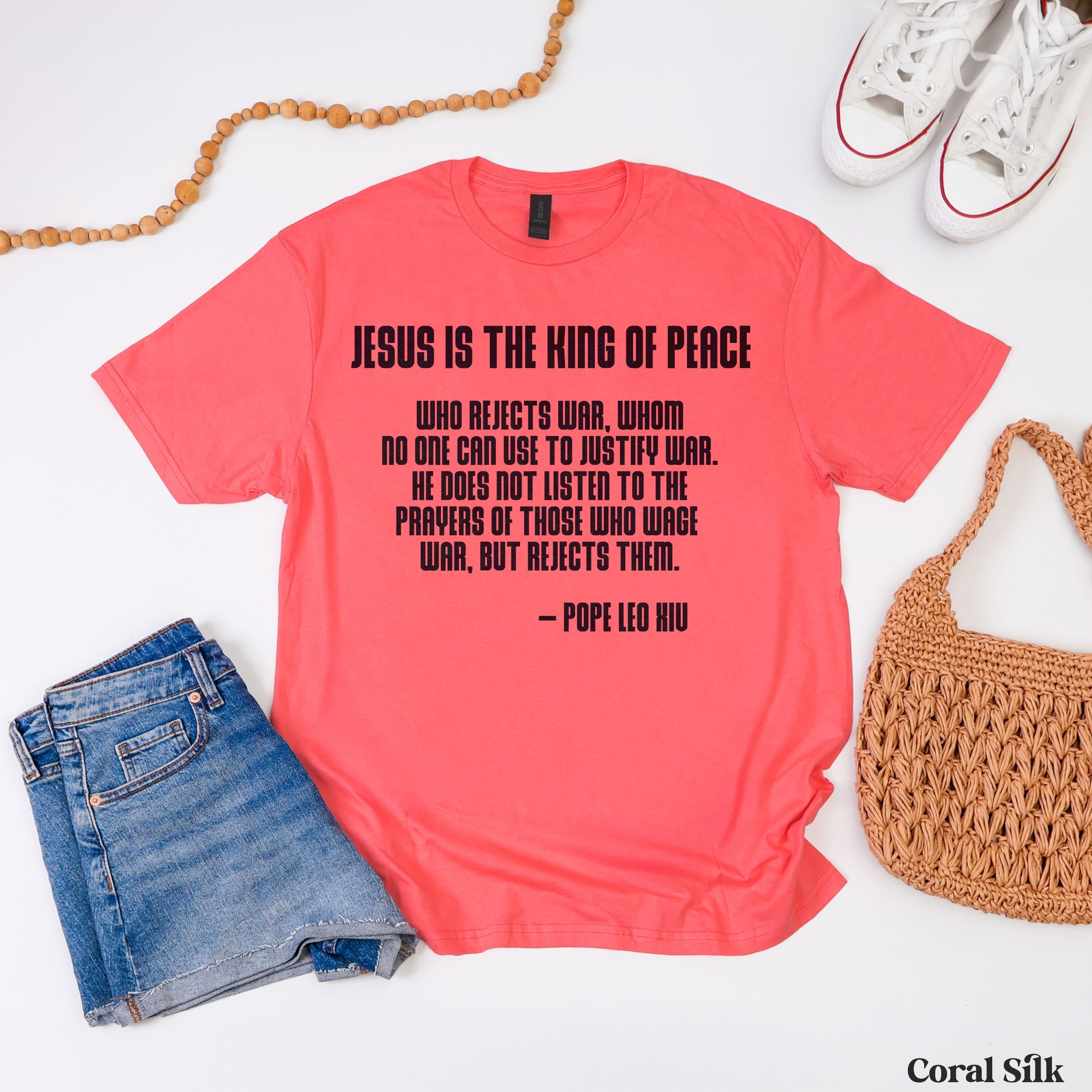 Coral pink t-shirt with black text about Jesus being the King of Peace.