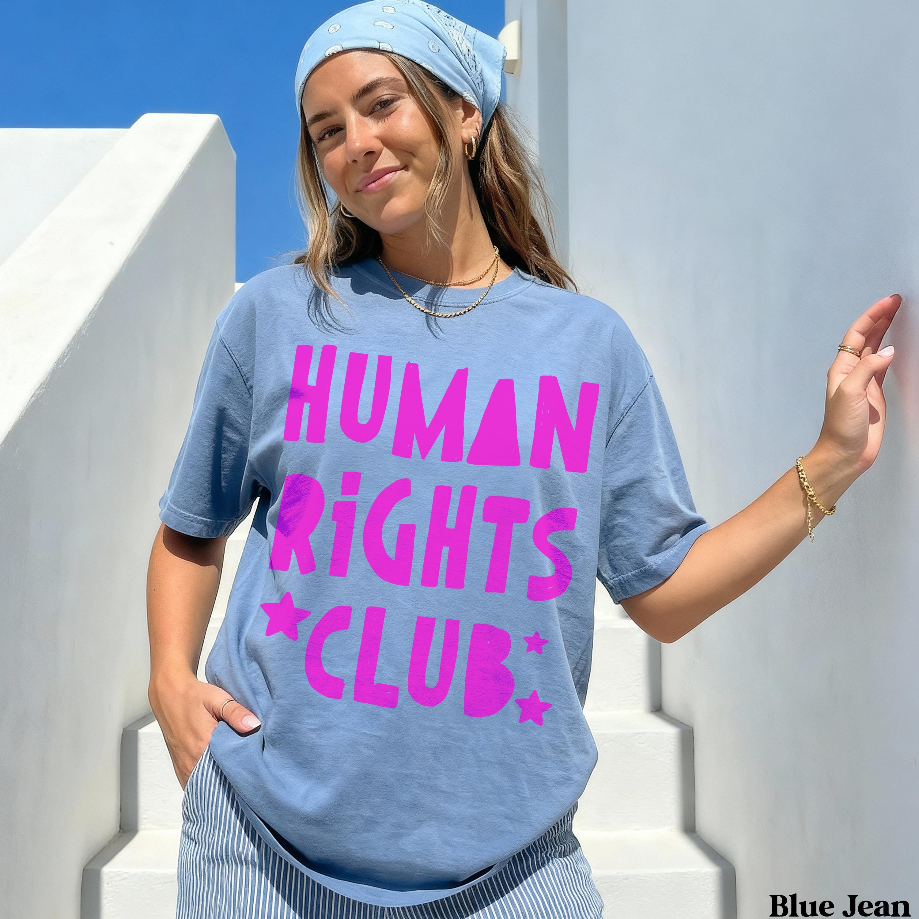 Blue t-shirt with "HUMAN RIGHTS CLUB" in pink text and stars, worn by a woman.
