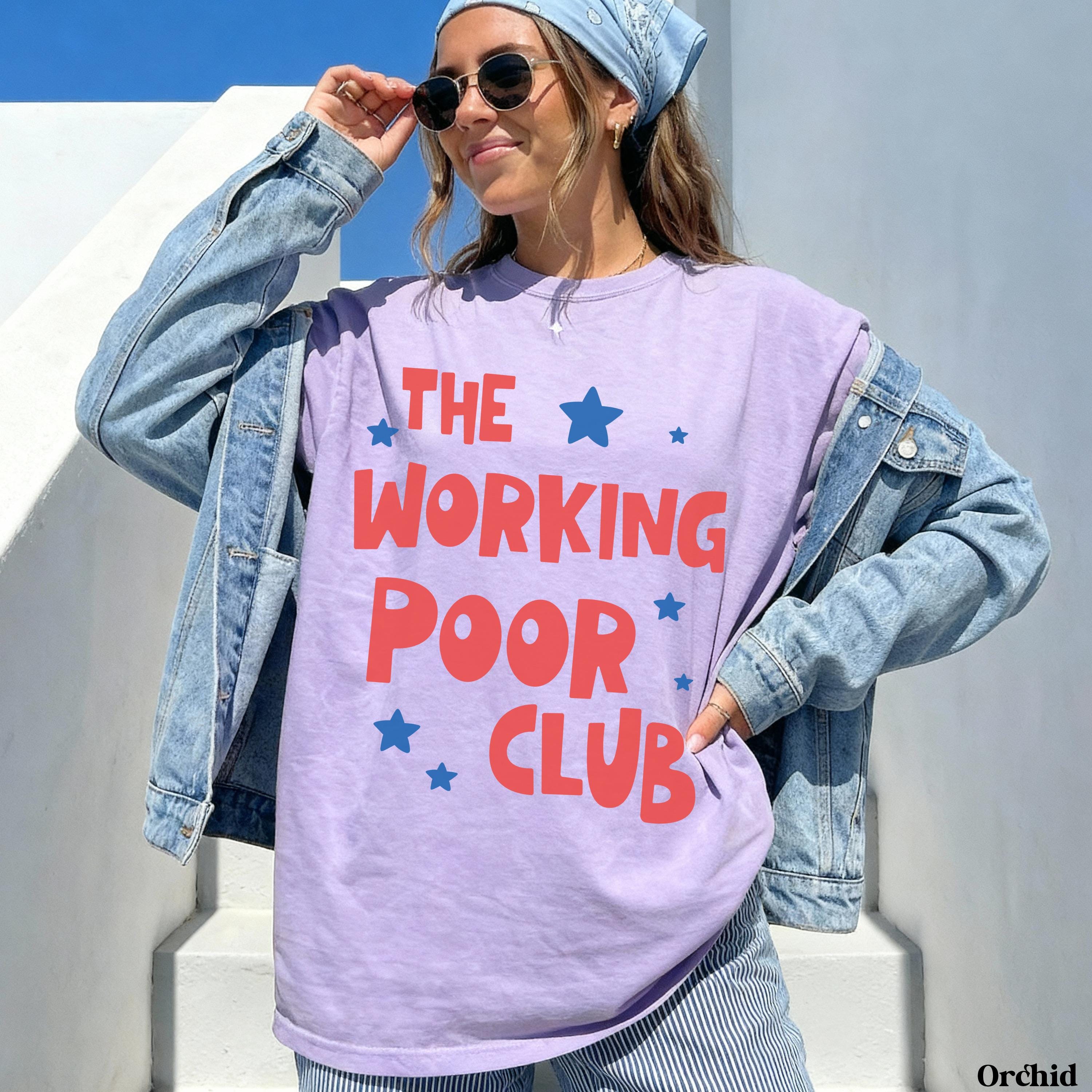 Woman wearing a lilac t-shirt with "THE WORKING POOR CLUB" text and blue stars.