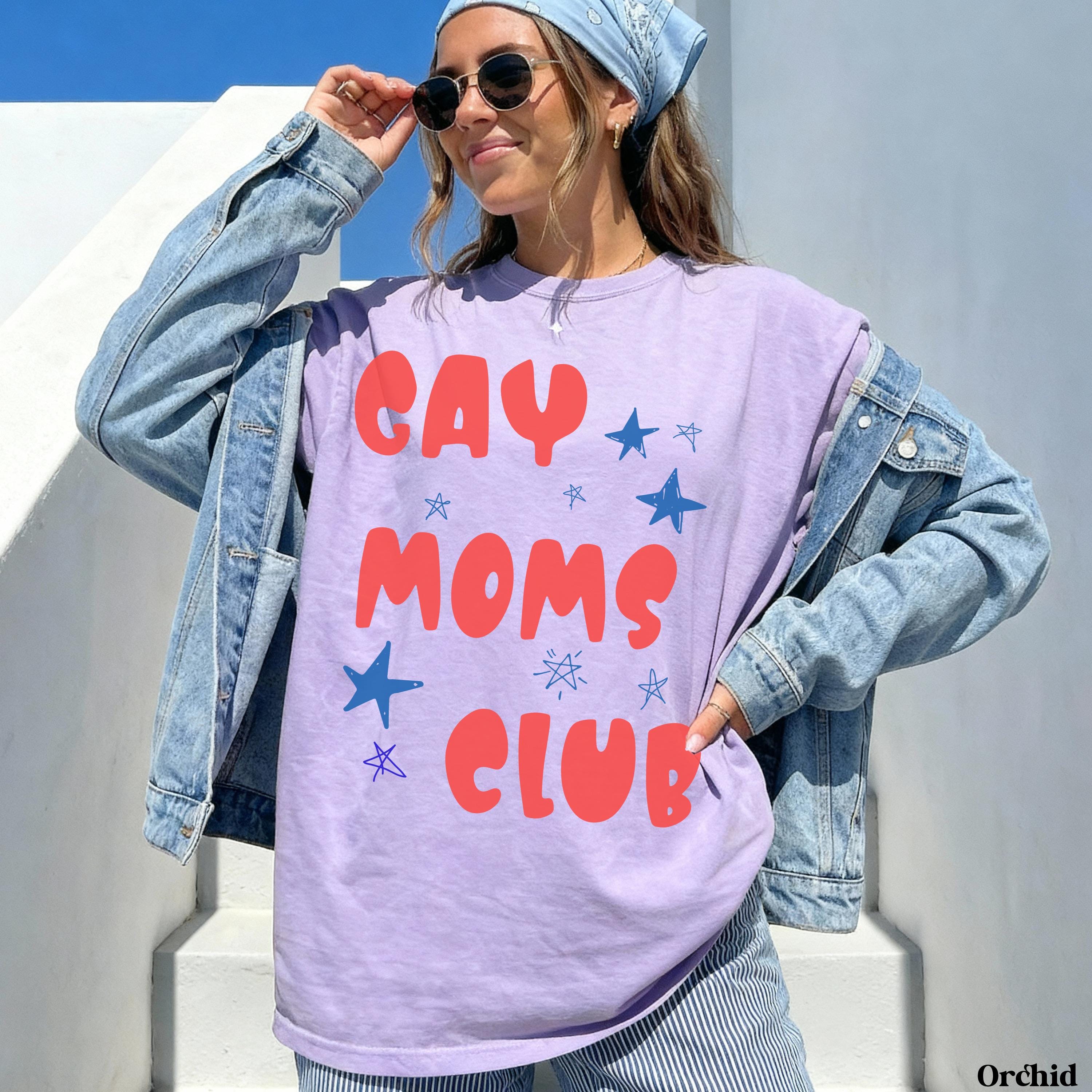 Lavender t-shirt with "GAY MOMS CLUB" in red lettering and blue stars.