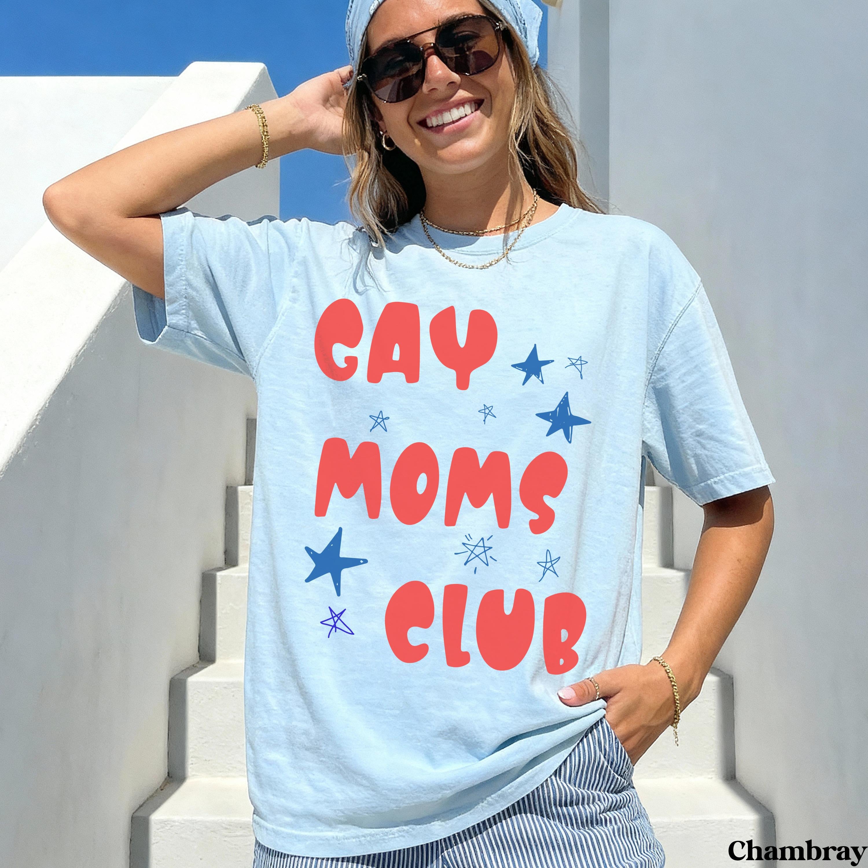 Light blue t-shirt with red and blue "GAY MOMS CLUB" text and stars.