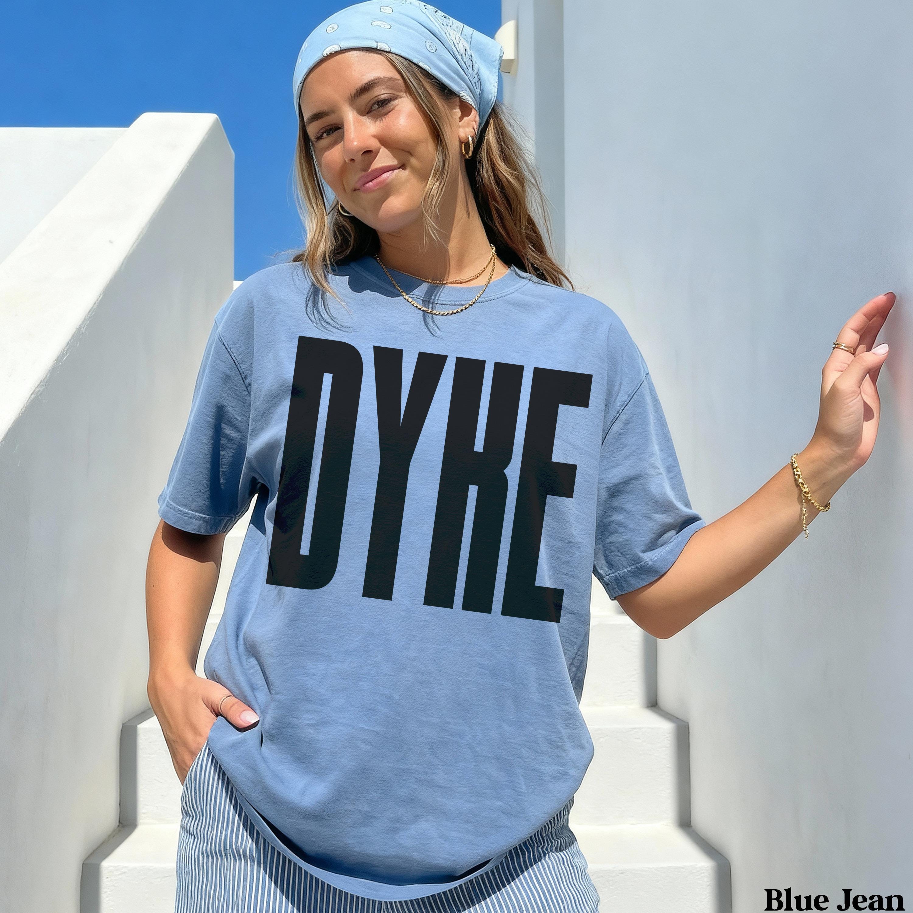 Woman wearing blue t-shirt with large black "DYKE" text.