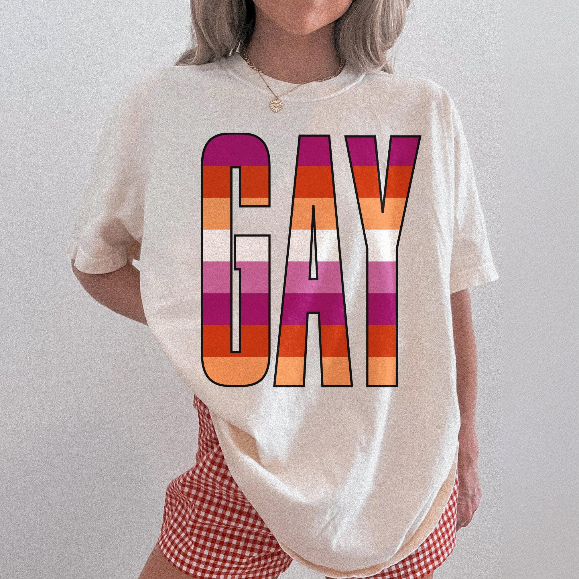Cream t-shirt with "GAY" in the lesbian pride flag colors.