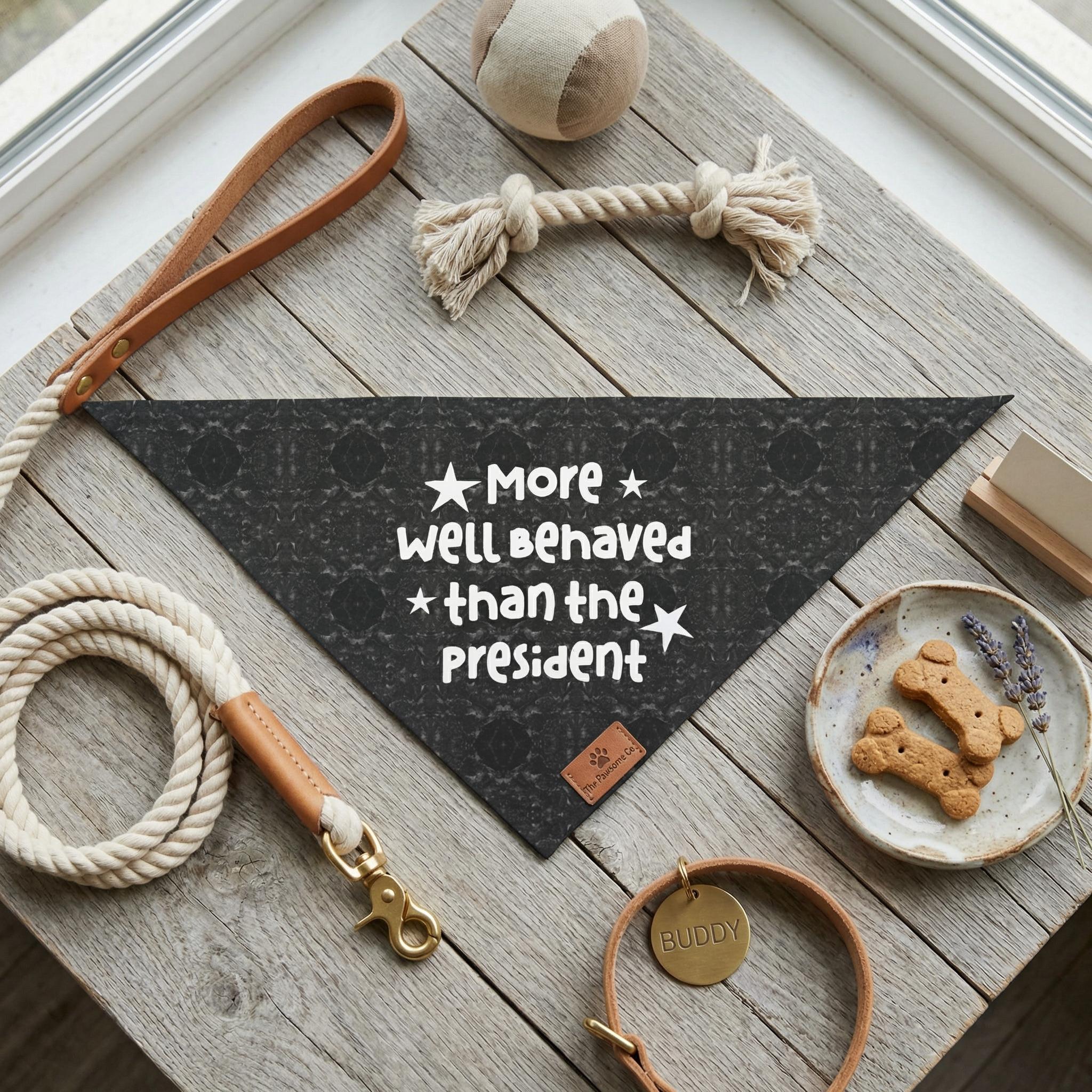 Black bandana with white text "More well behaved than the President" for a dog.
