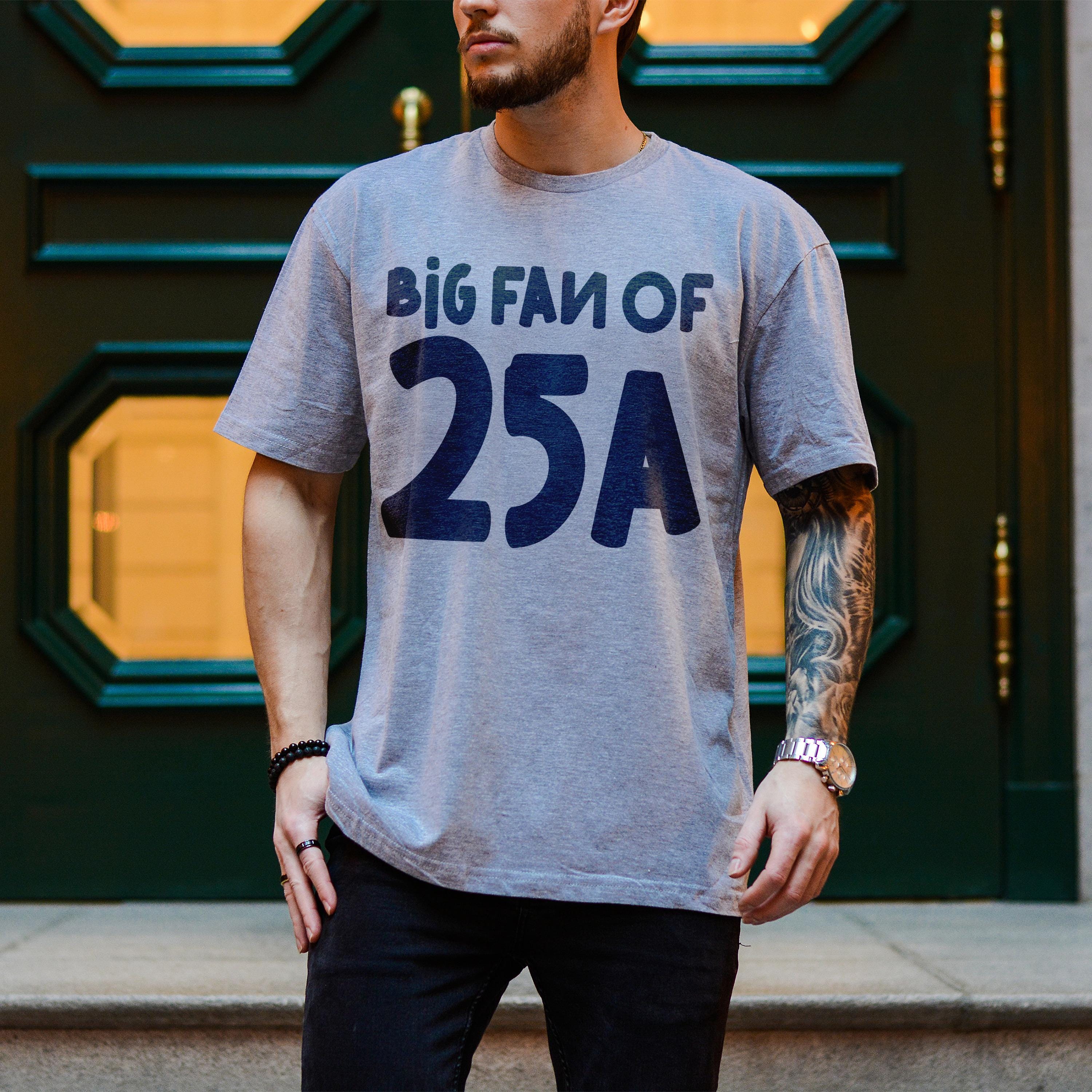 Gray t-shirt with "BIG FAN OF 25A" text, worn by a man.