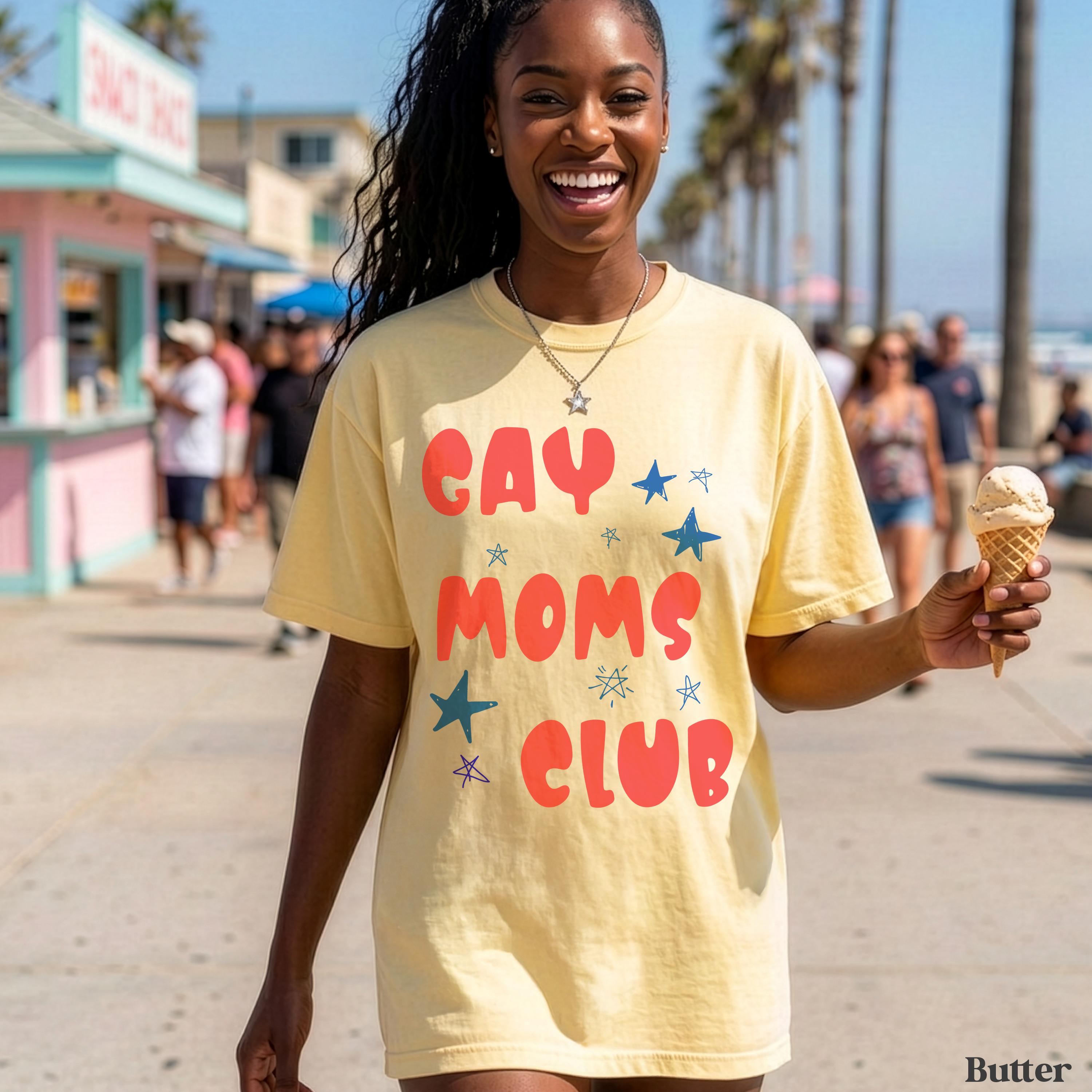 Woman wearing yellow "GAY MOMS CLUB" t-shirt holds ice cream cone on beach.