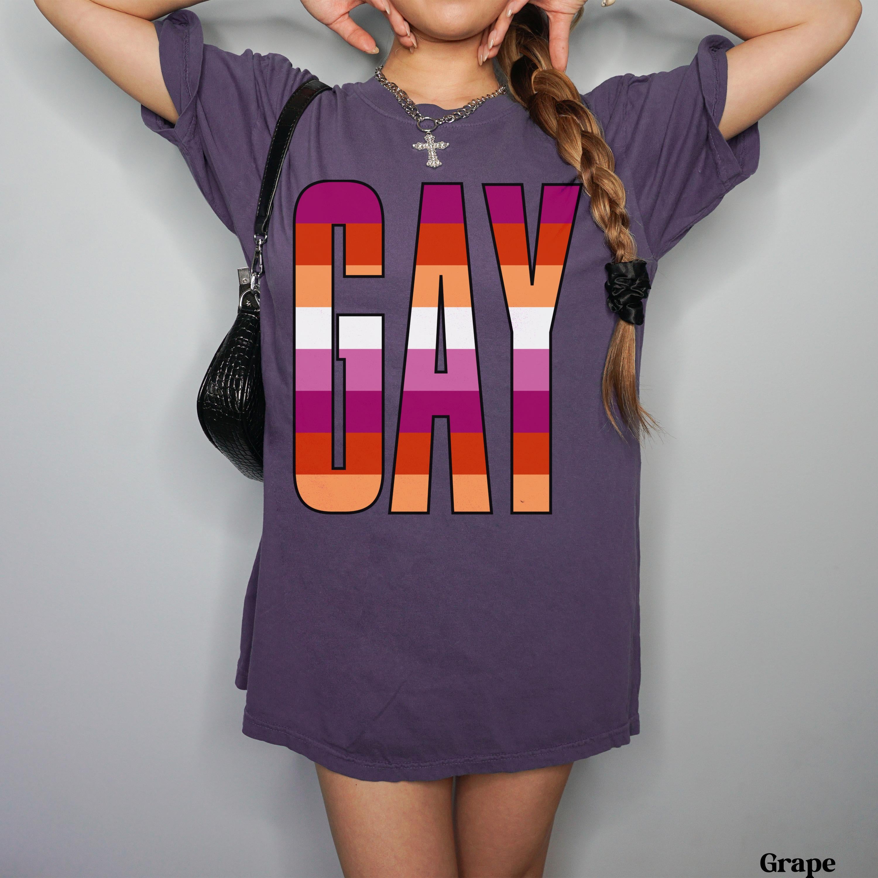 Purple t-shirt with "GAY" in rainbow stripes, worn by a person.