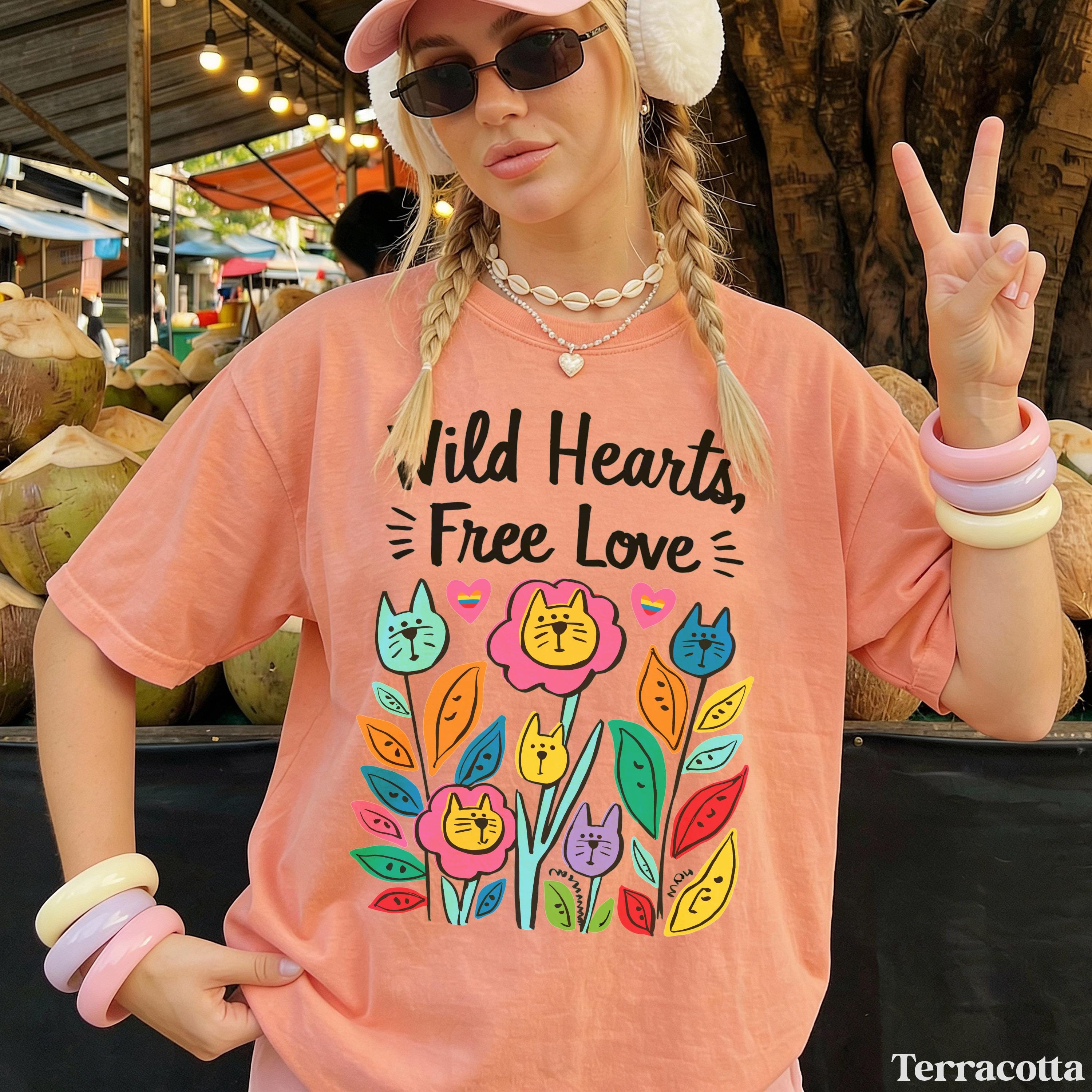 Peach t-shirt with "Wild Hearts, Free Love" and colorful cat flowers.