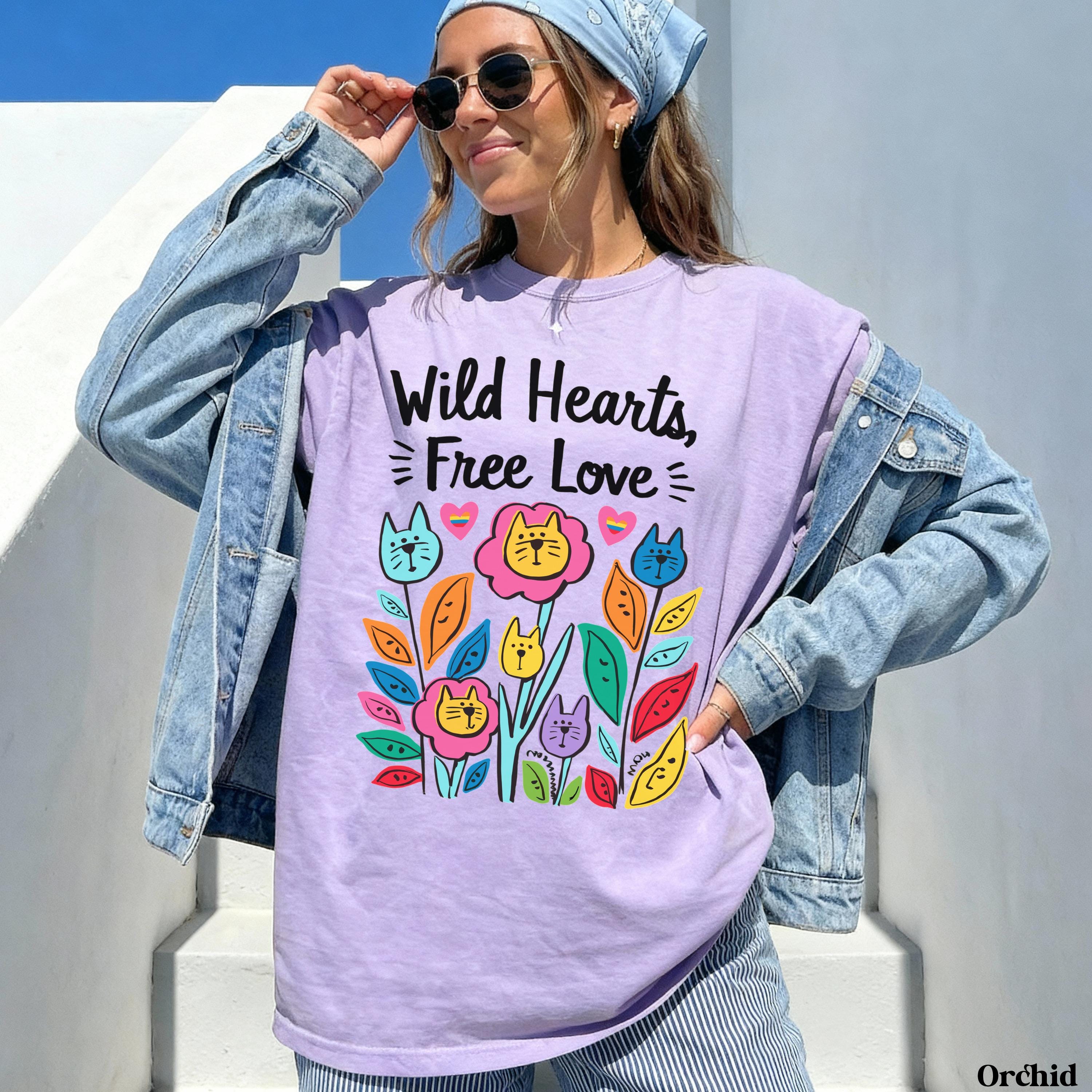 Woman in purple t-shirt with "Wild Hearts, Free Love" text and colorful cat flowers.