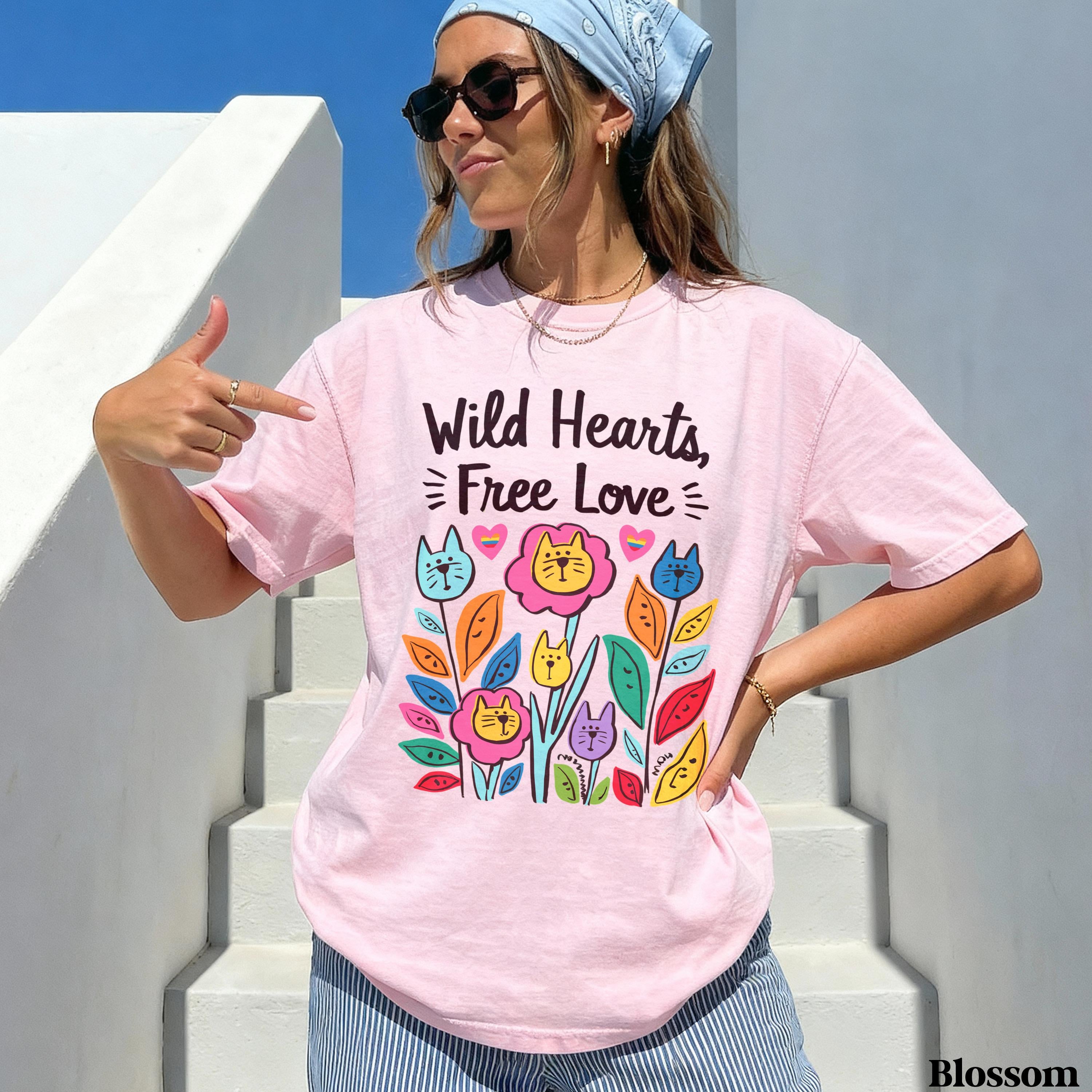 Pink t-shirt with colorful floral cat design and text "Wild Hearts, Free Love."