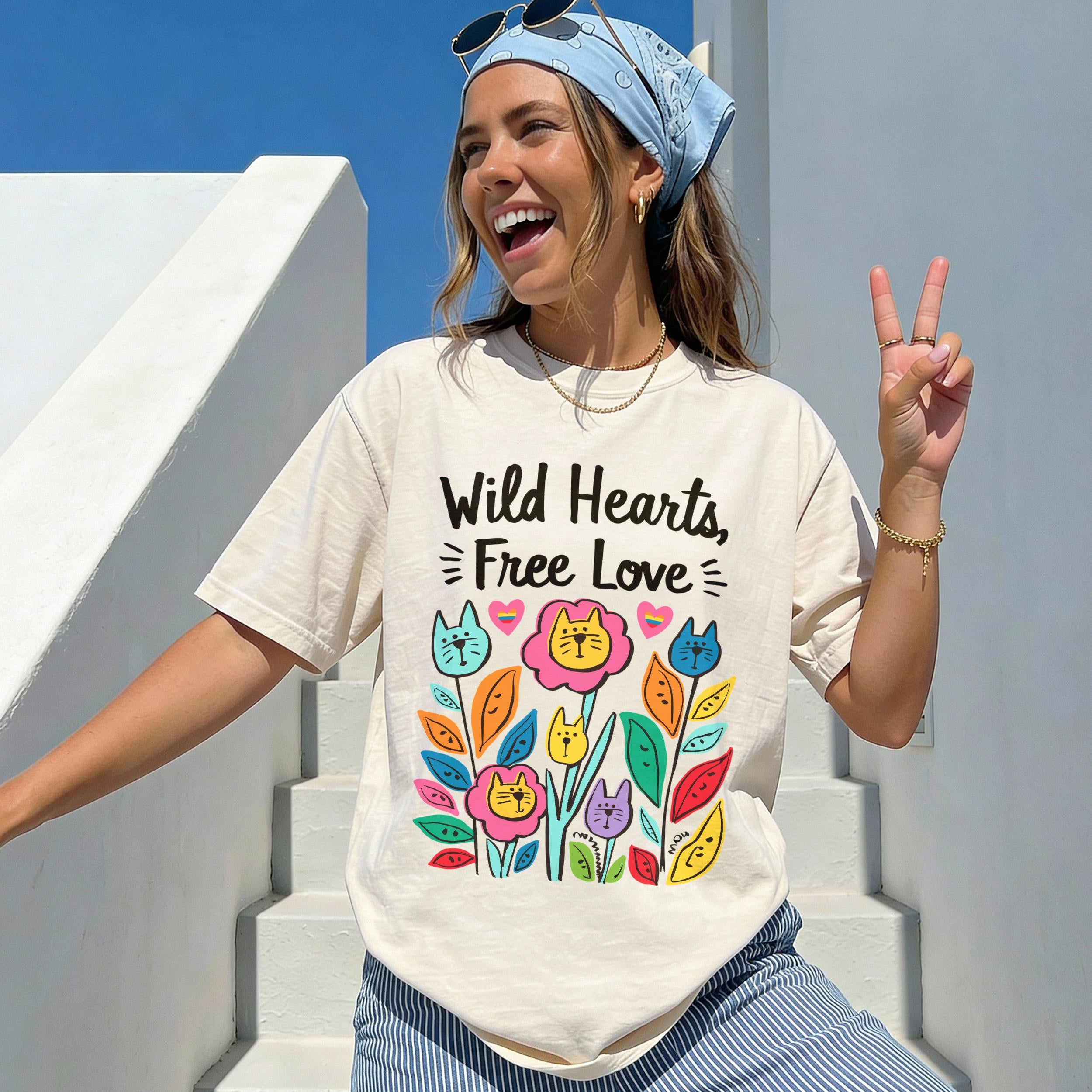 Woman wearing a cream t-shirt with "Wild Hearts, Free Love" and floral cat design.