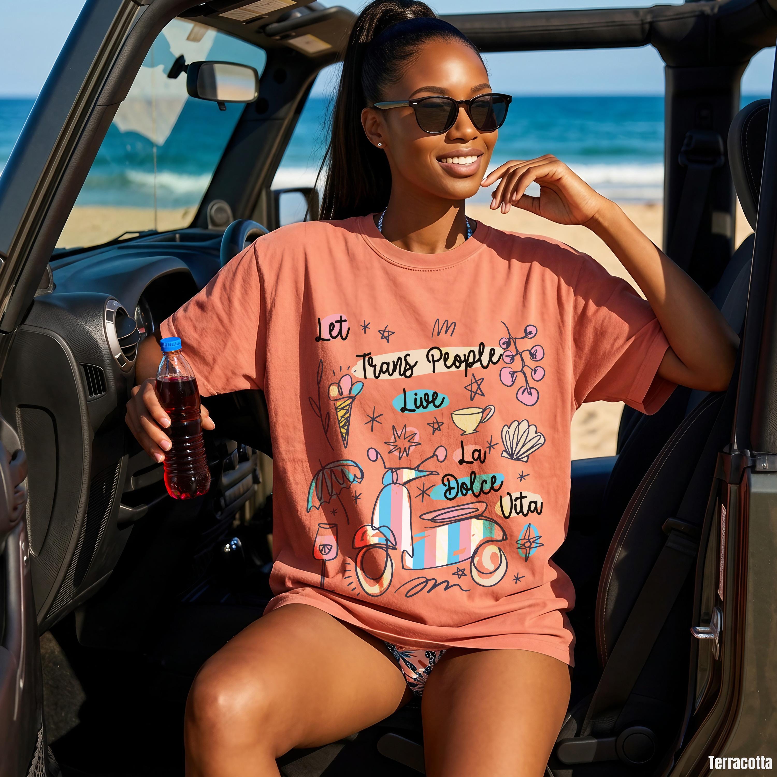 Woman in terracotta t-shirt with "Let Trans People Live La Dolce Vita" graphic.