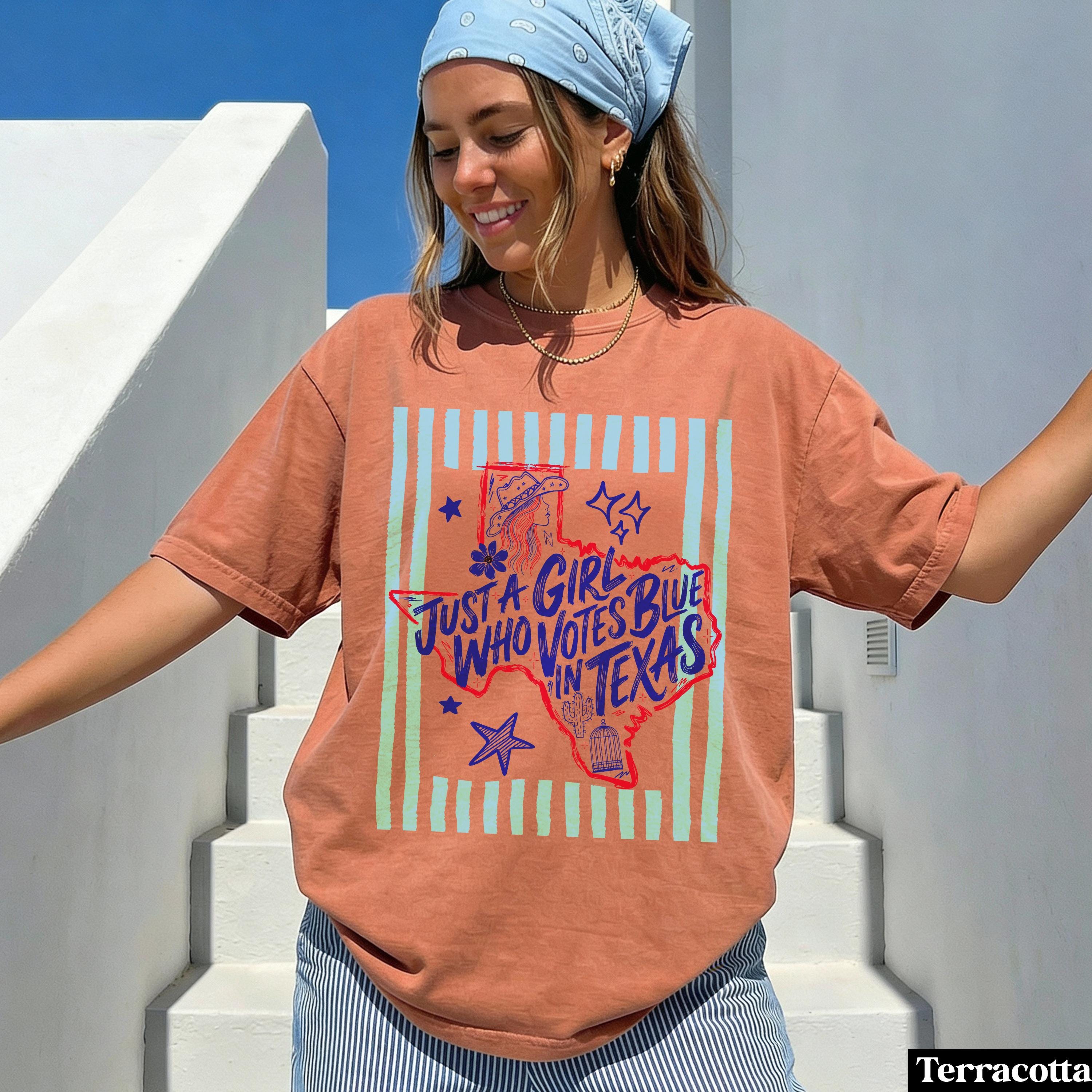 Woman wearing a terracotta t-shirt with "Just a Girl Who Votes Blue in Texas" graphic.