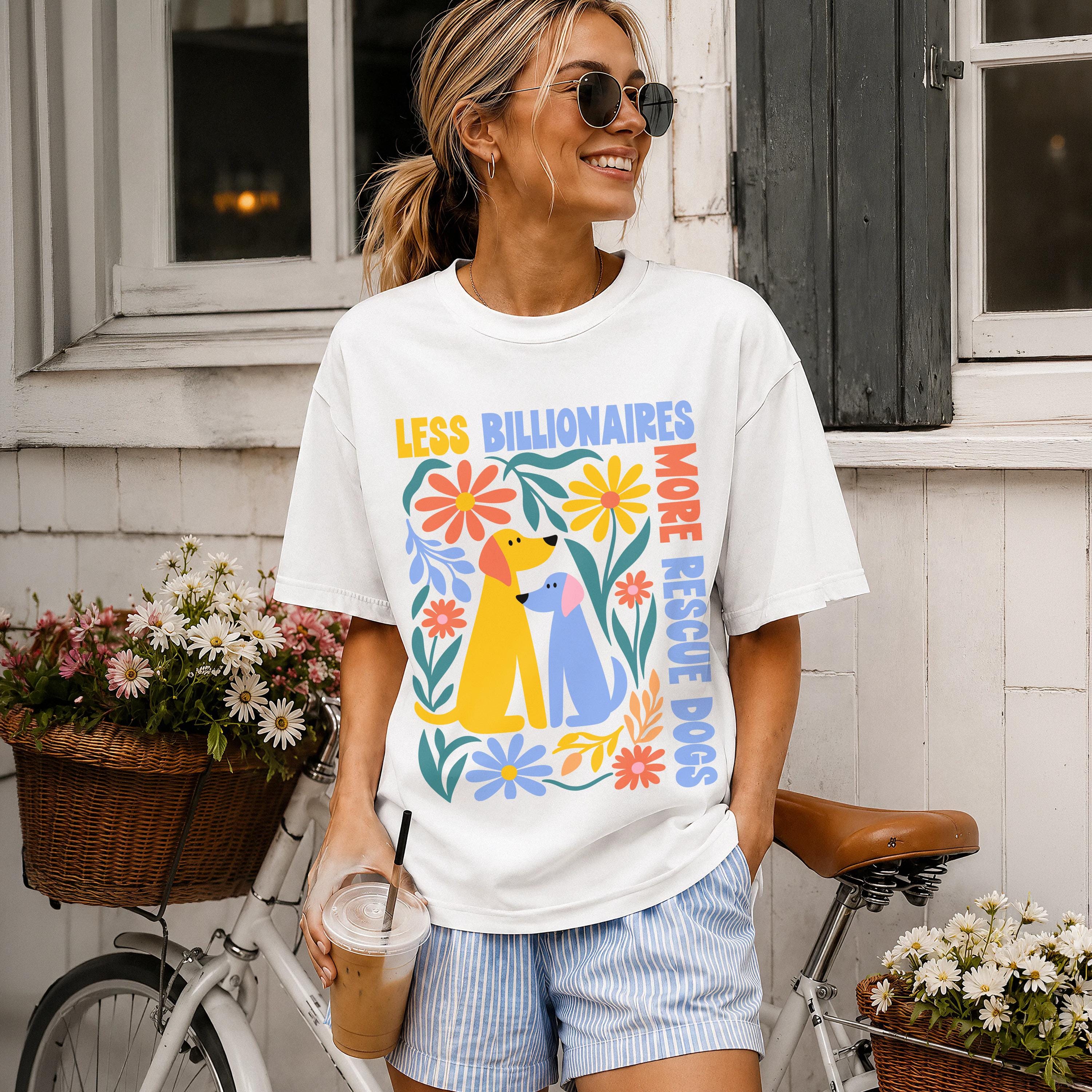 Woman wearing white t-shirt with "Less Billionaires, More Rescue Dogs" and dog graphics.