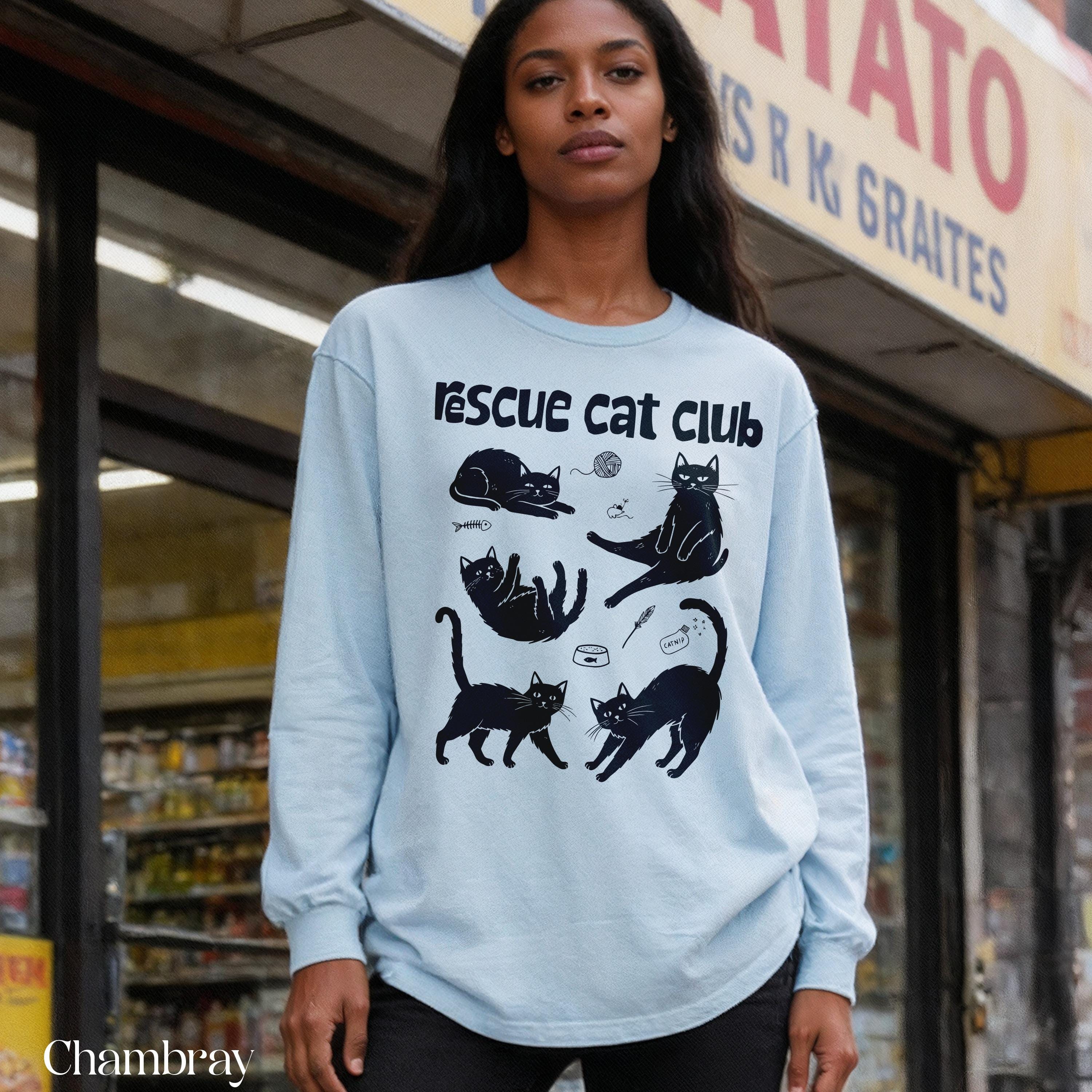 Light blue long-sleeve shirt with "Rescue Cat Club" and cat graphic designs.