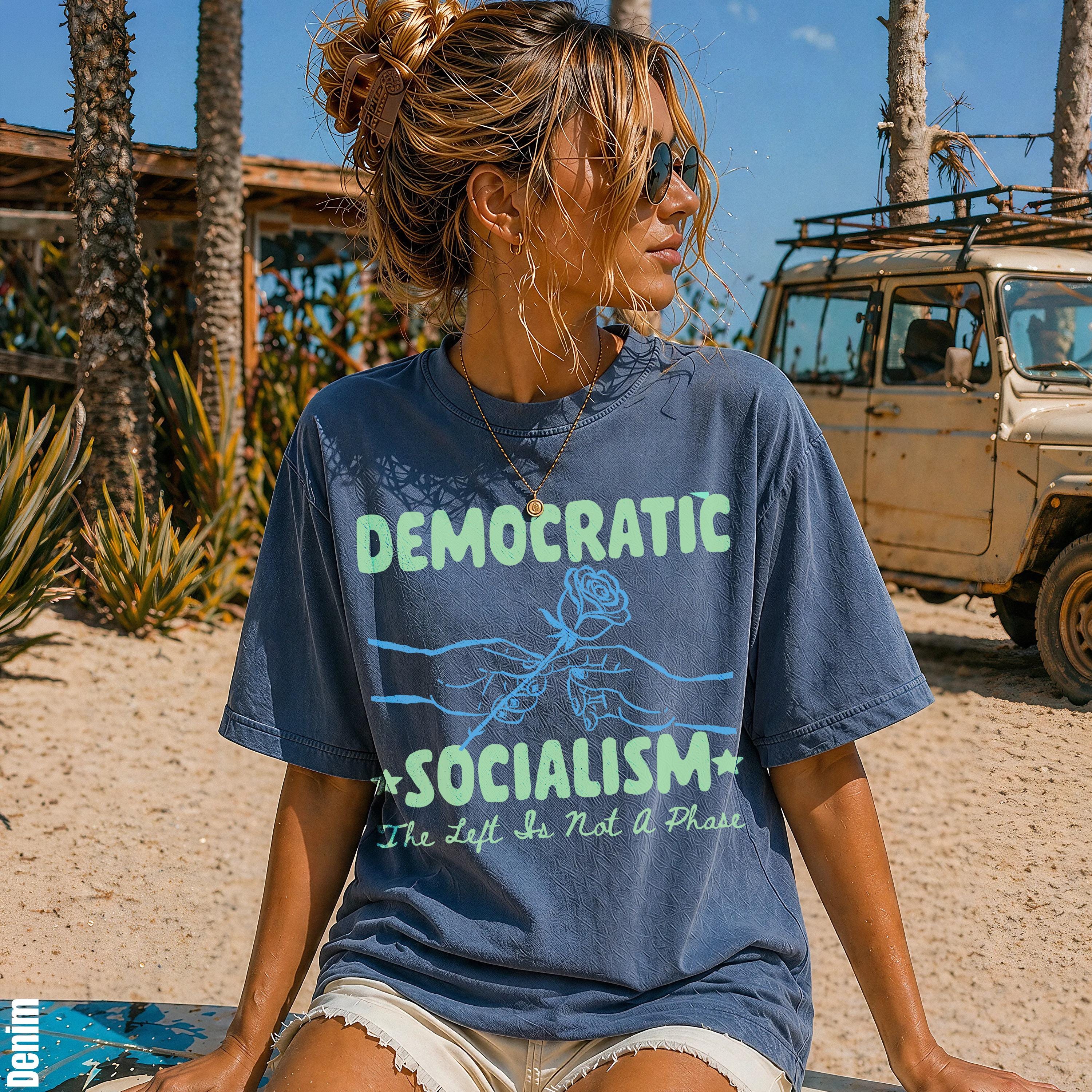 Blue t-shirt with text "DEMOCRATIC SOCIALISM The Left Is Not A Phase" and graphic of hands holding a rose.