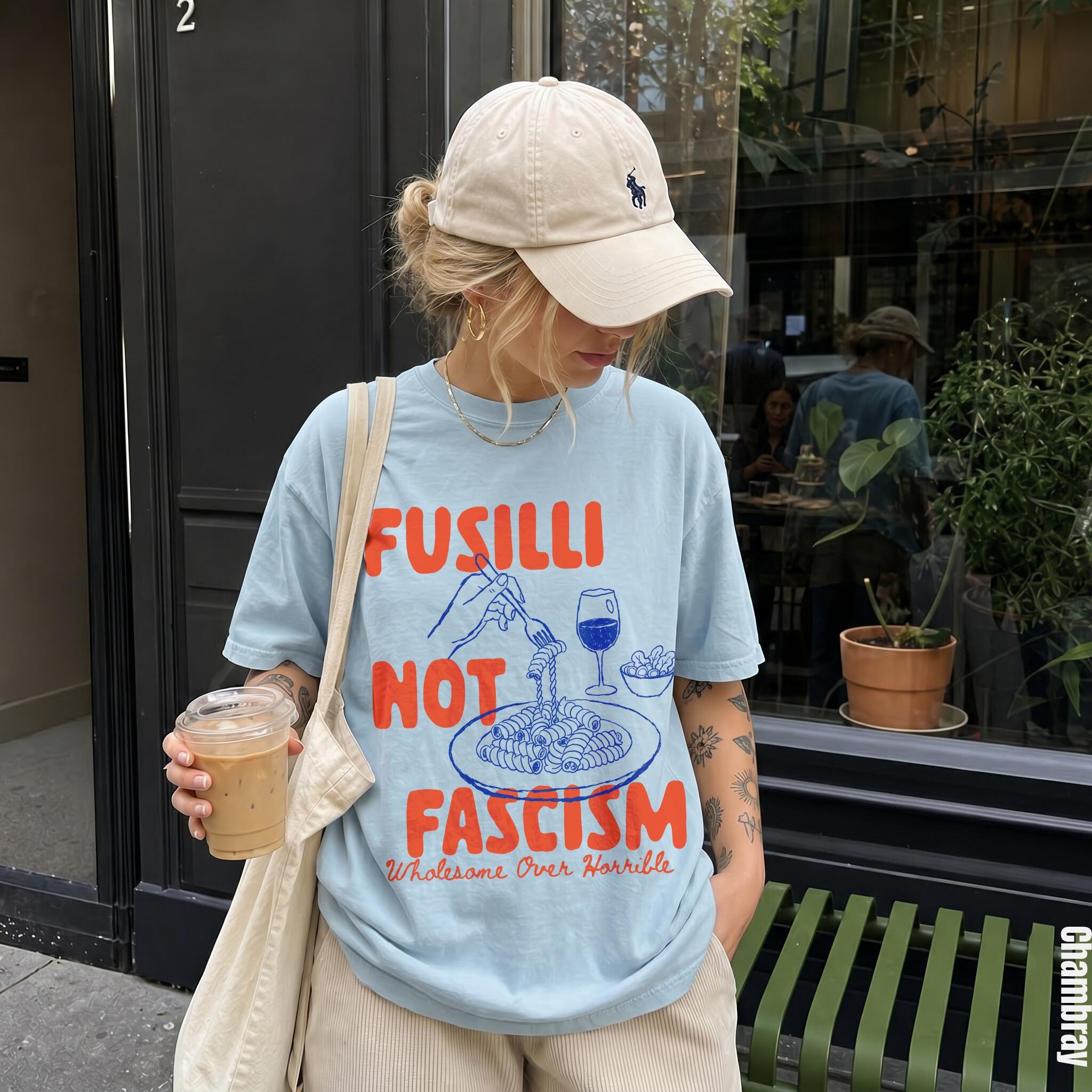 Light blue t-shirt with "Fusilli Not Fascism" graphic and a coffee cup.
