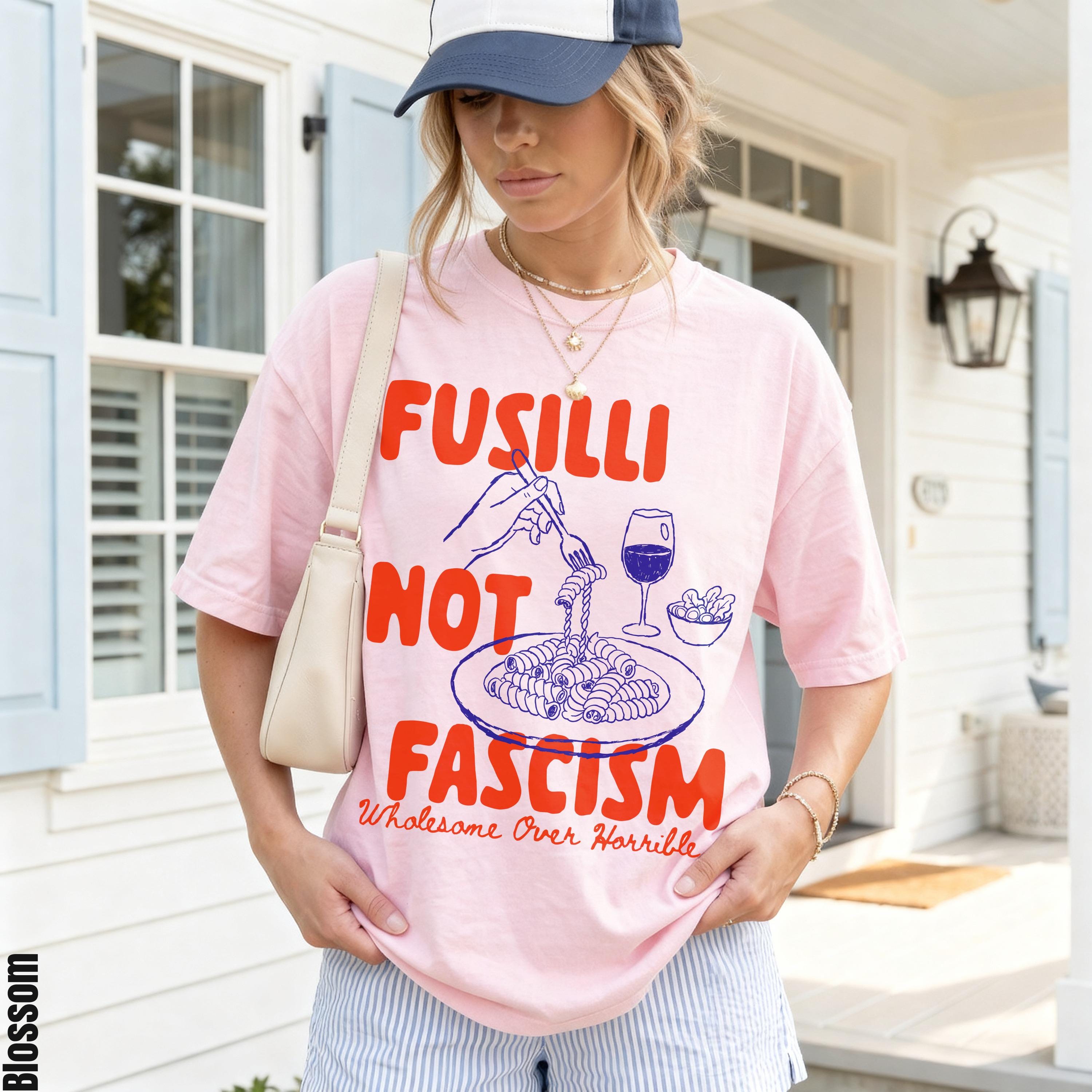 Pink t-shirt with "Fusilli Not Fascism" text, pasta illustration, and a glass of wine.