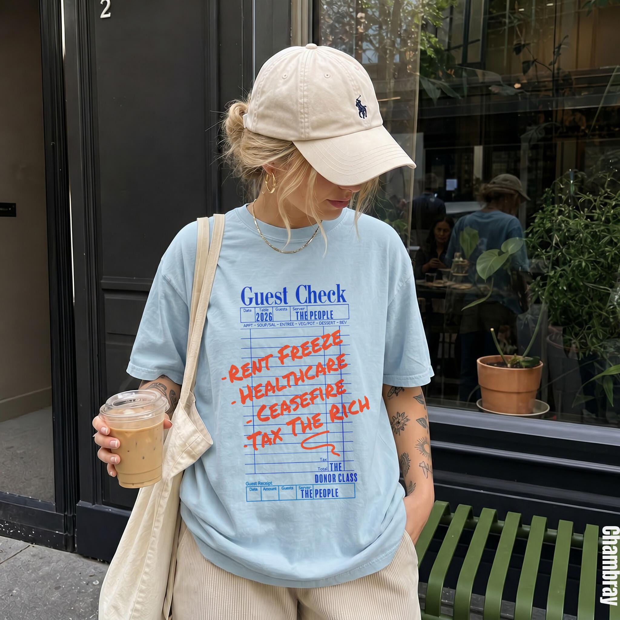 Light blue t-shirt with "Guest Check" text and "Rent Freeze, Healthcare, Ceasefire, Tax the Rich" slogans.