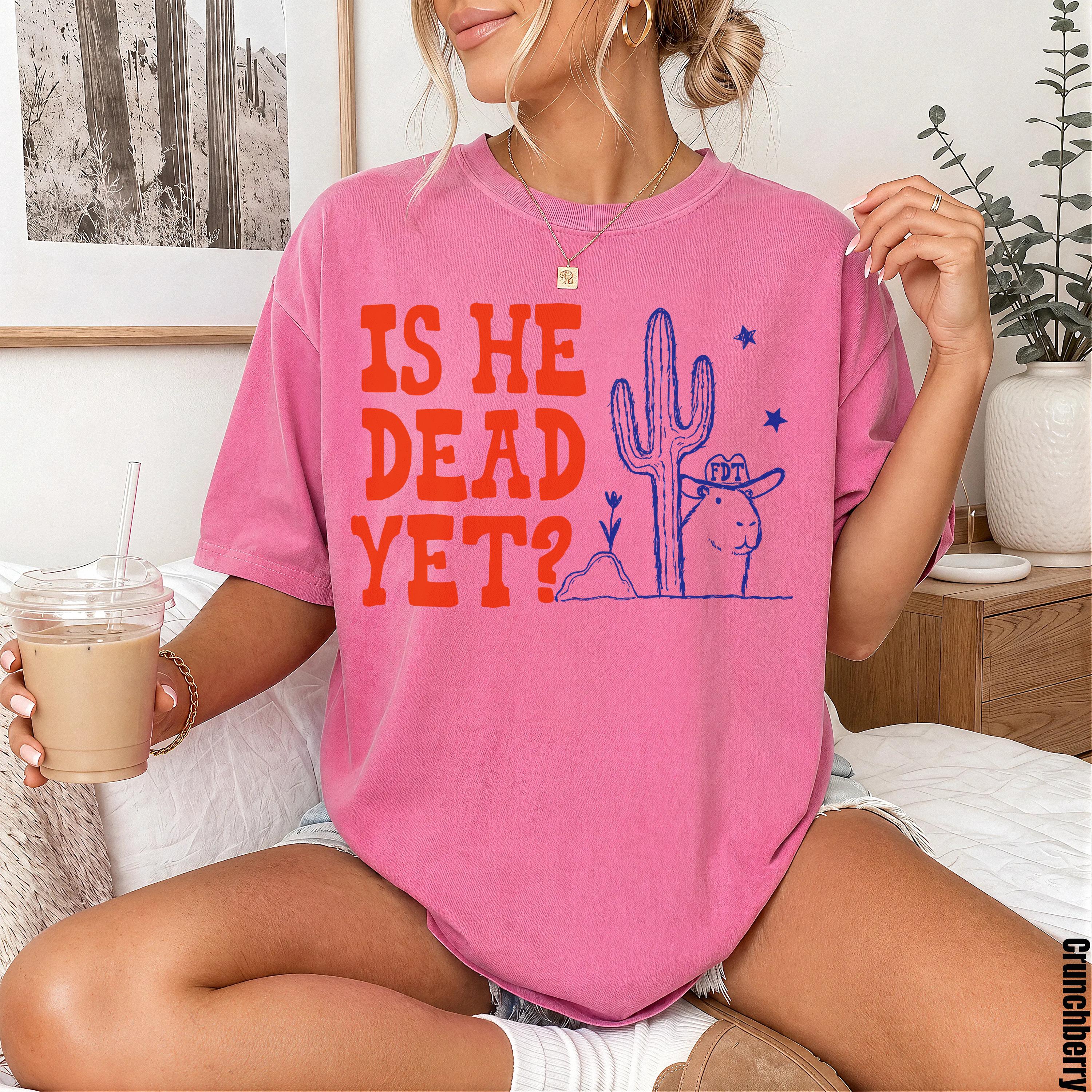 Pink t-shirt with "IS HE DEAD YET?" graphic featuring a cowboy hat-wearing prairie dog and cactus.