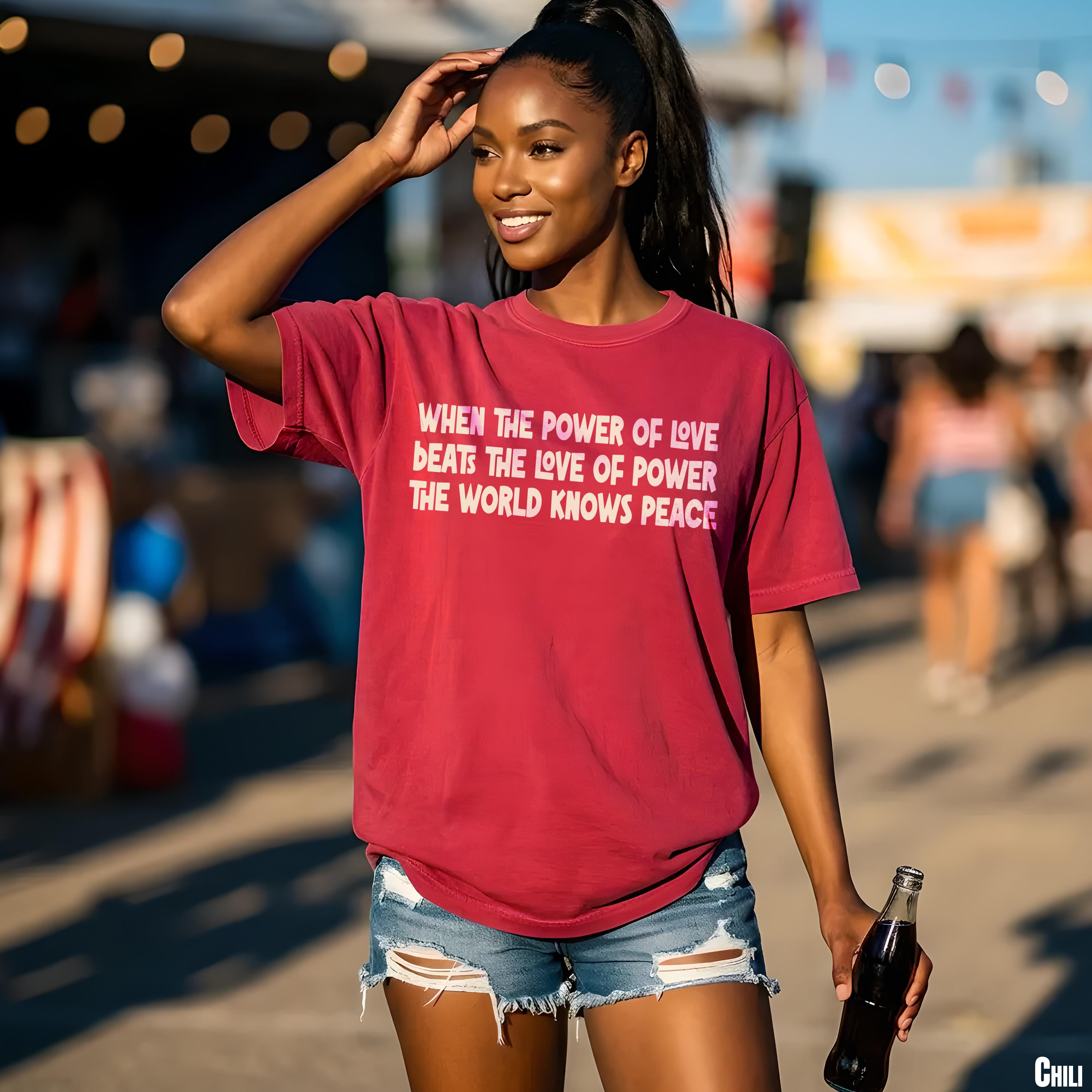 Woman in red t-shirt with text "When the power of love beats the love of power, the world knows peace."