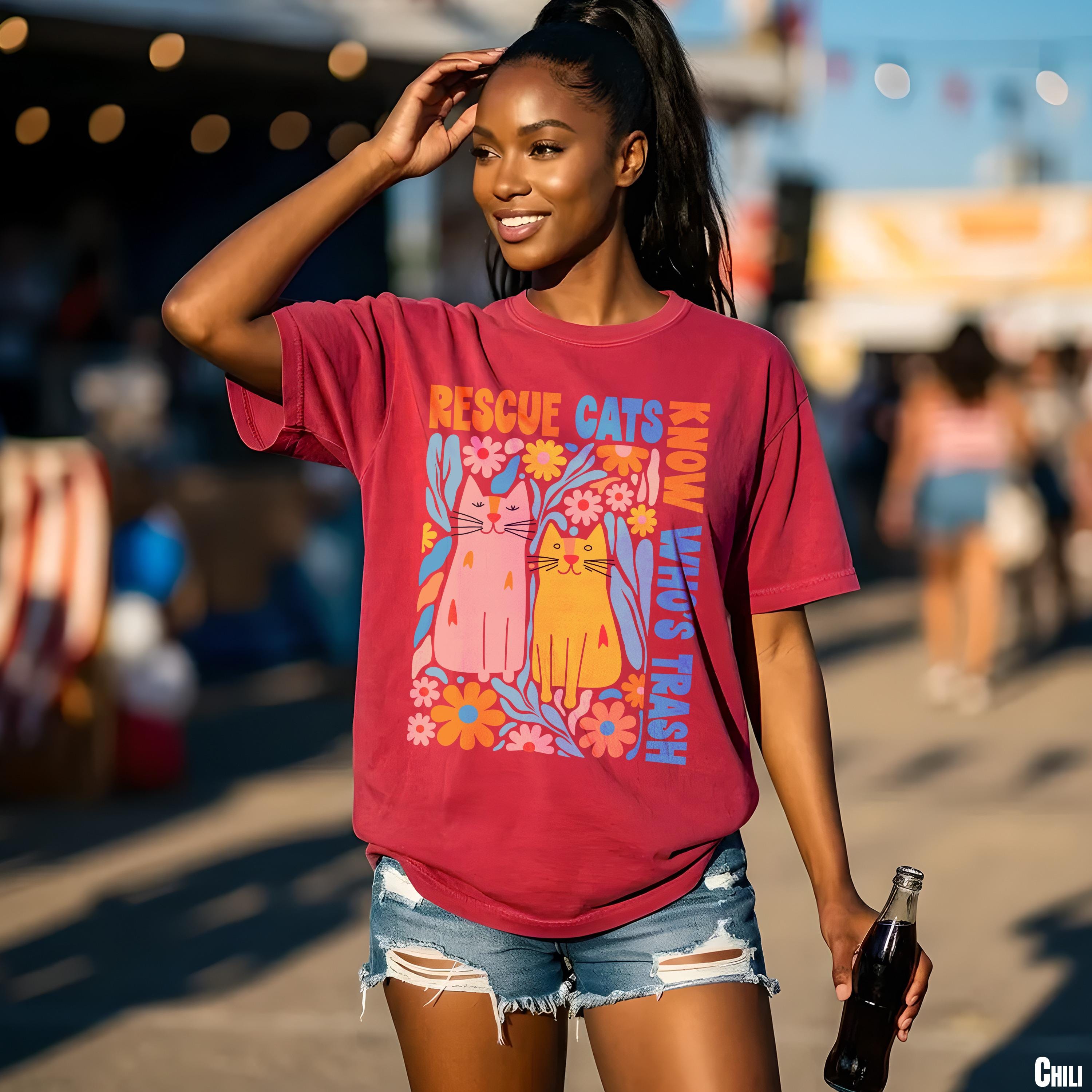 Crimson t-shirt with colorful cat and floral graphic and text.