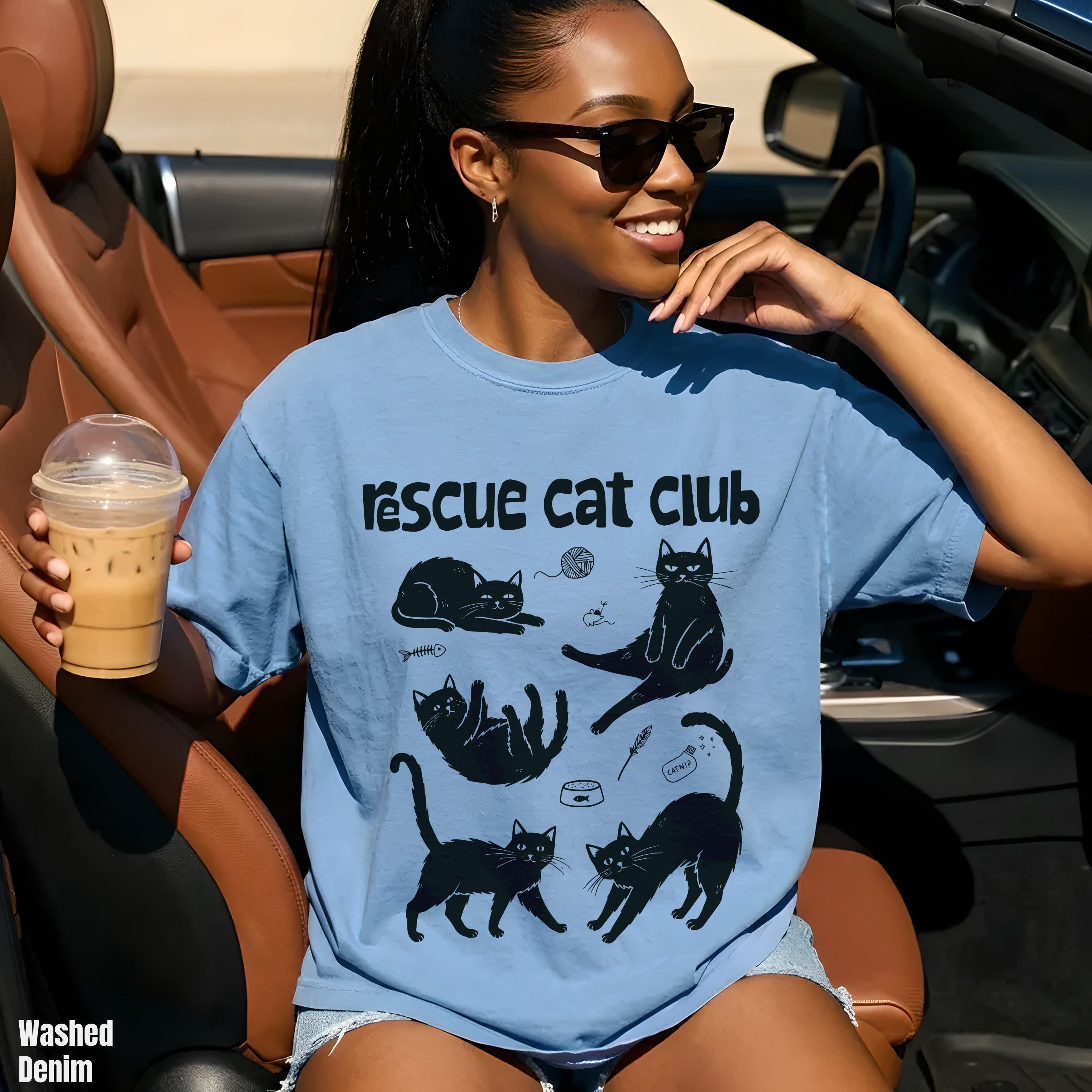 Woman wearing blue t-shirt with "Rescue Cat Club" and cat illustrations.