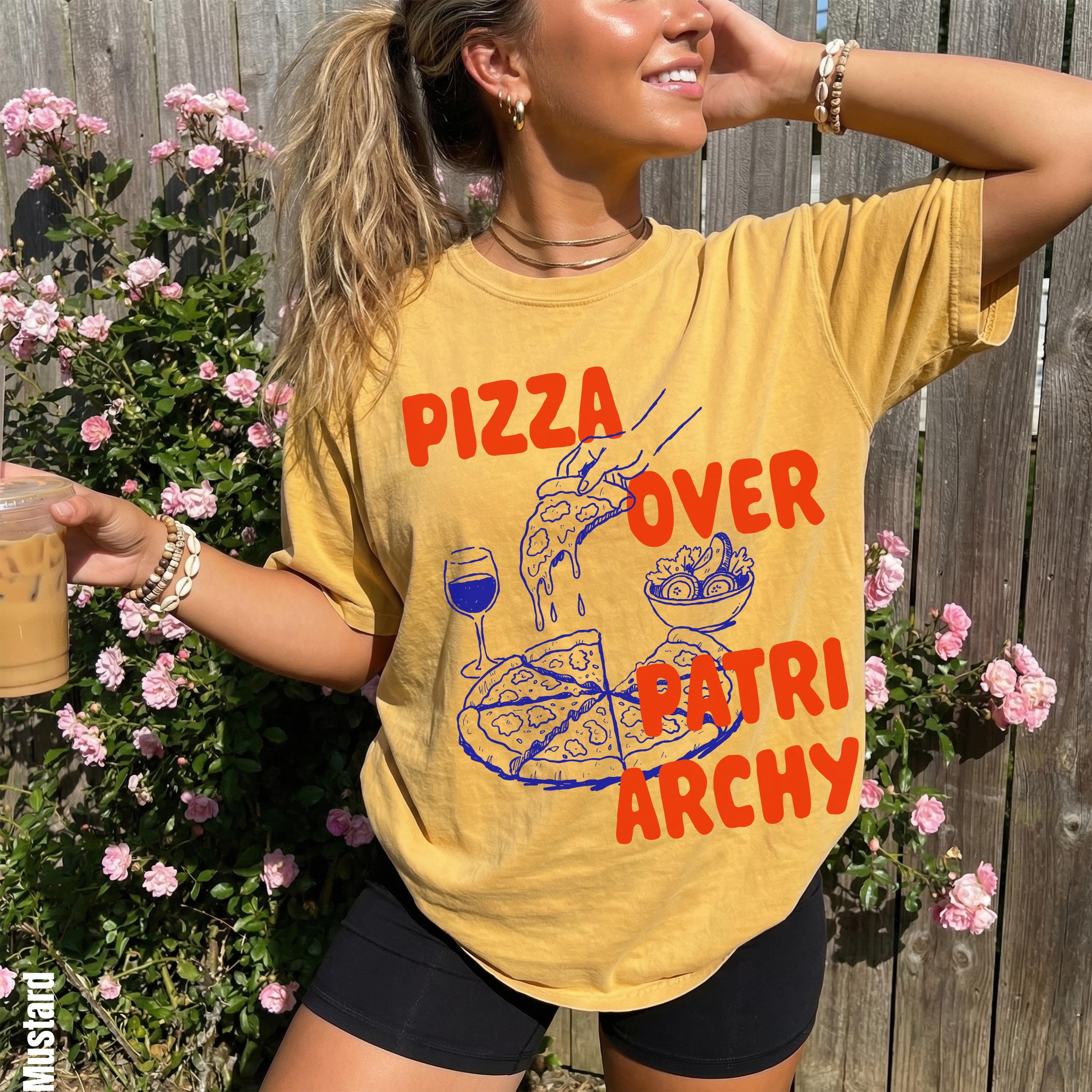 Yellow t-shirt with "Pizza Over Patriarchy" graphic, pizza, and wine illustration.