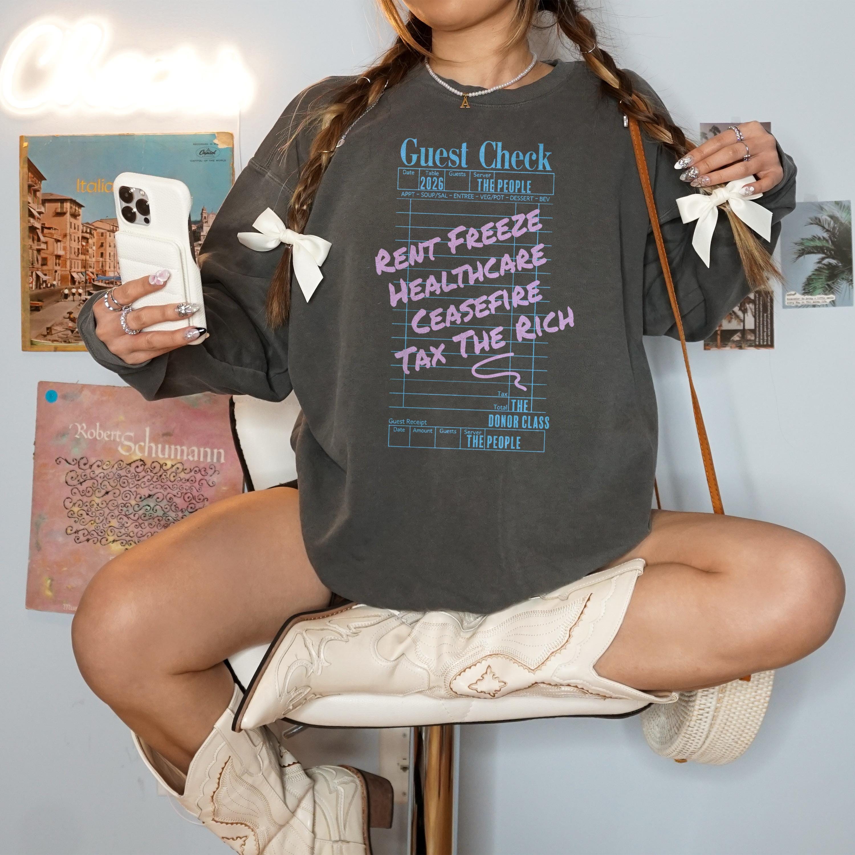 Gray sweatshirt with "Guest Check" graphic listing "Rent Freeze, Healthcare, Ceasefire, Tax The Rich."